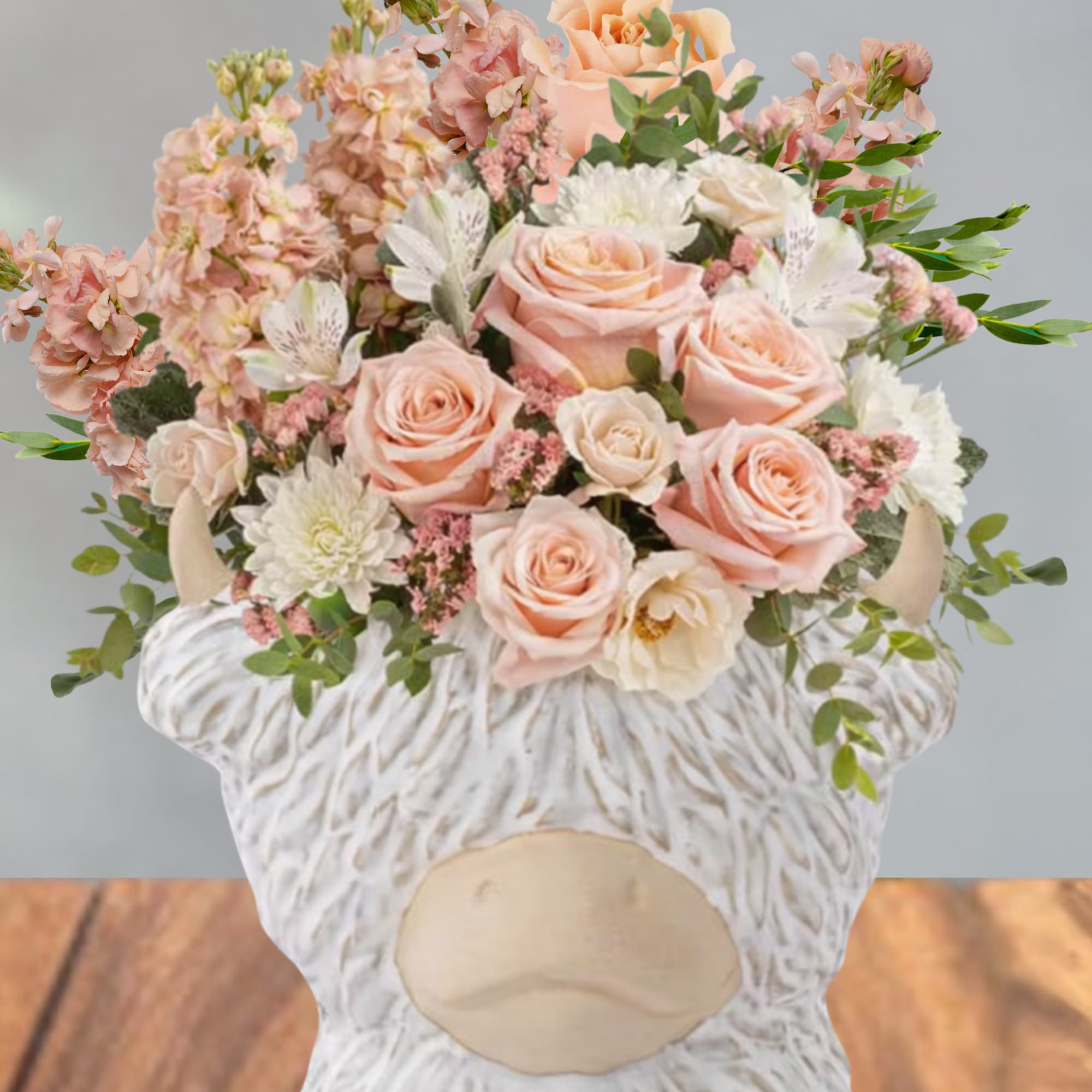 Soft peach roses and blush blooms gathered in a compact, rounded bouquet