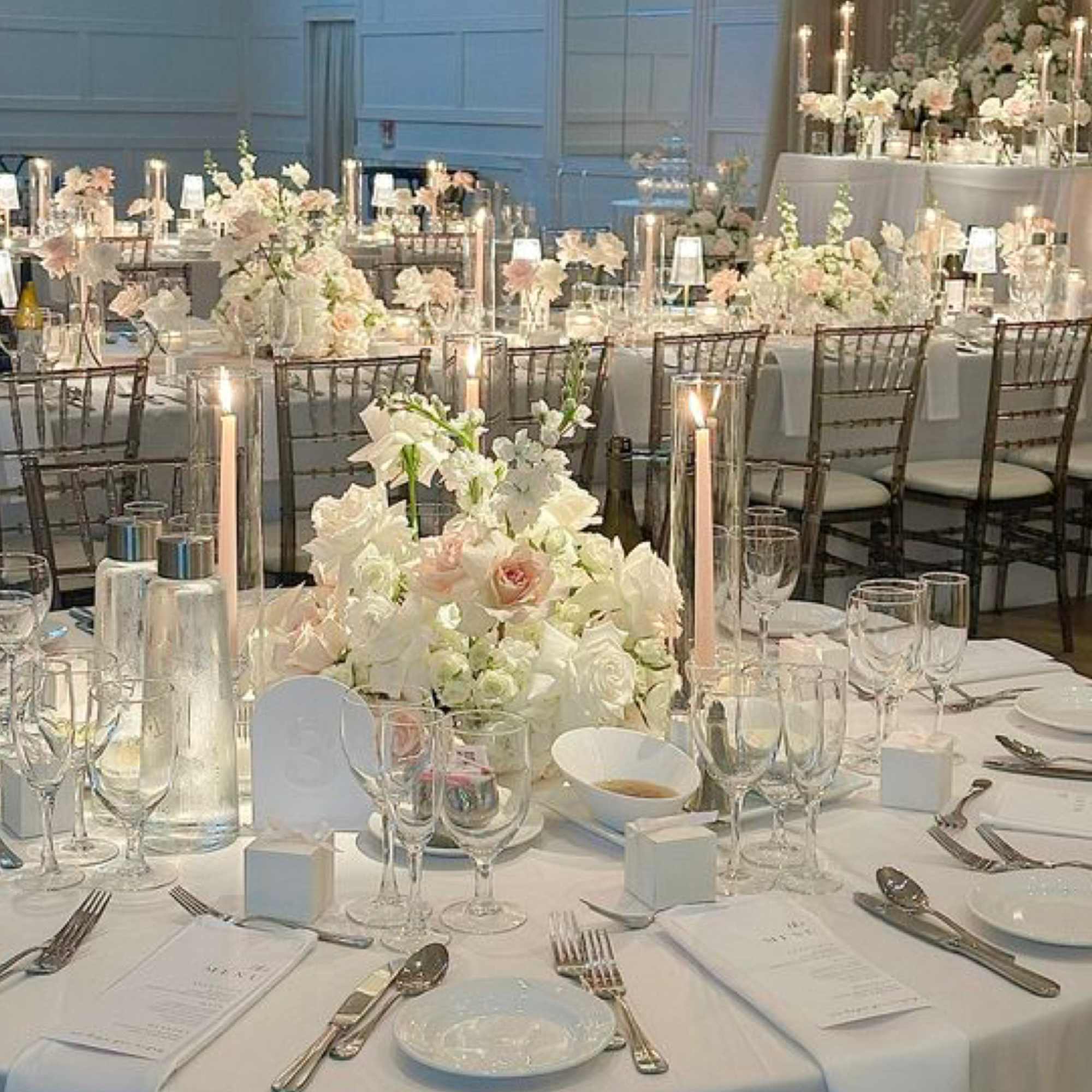 White and blush floral centerpieces on a wedding reception table with candles