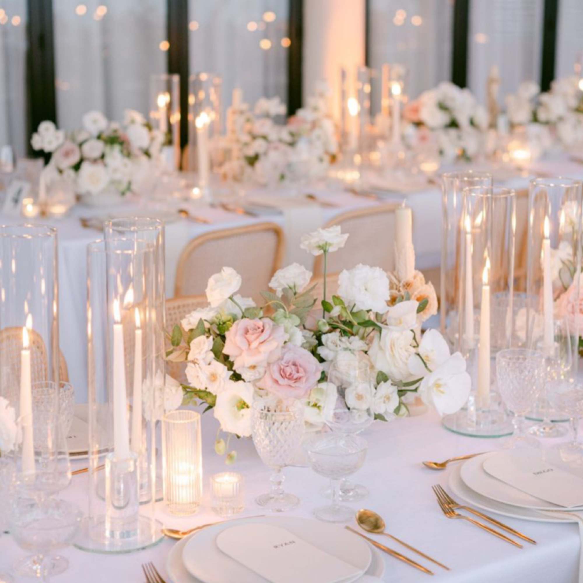 White and blush floral centerpieces on a candlelit banquet table