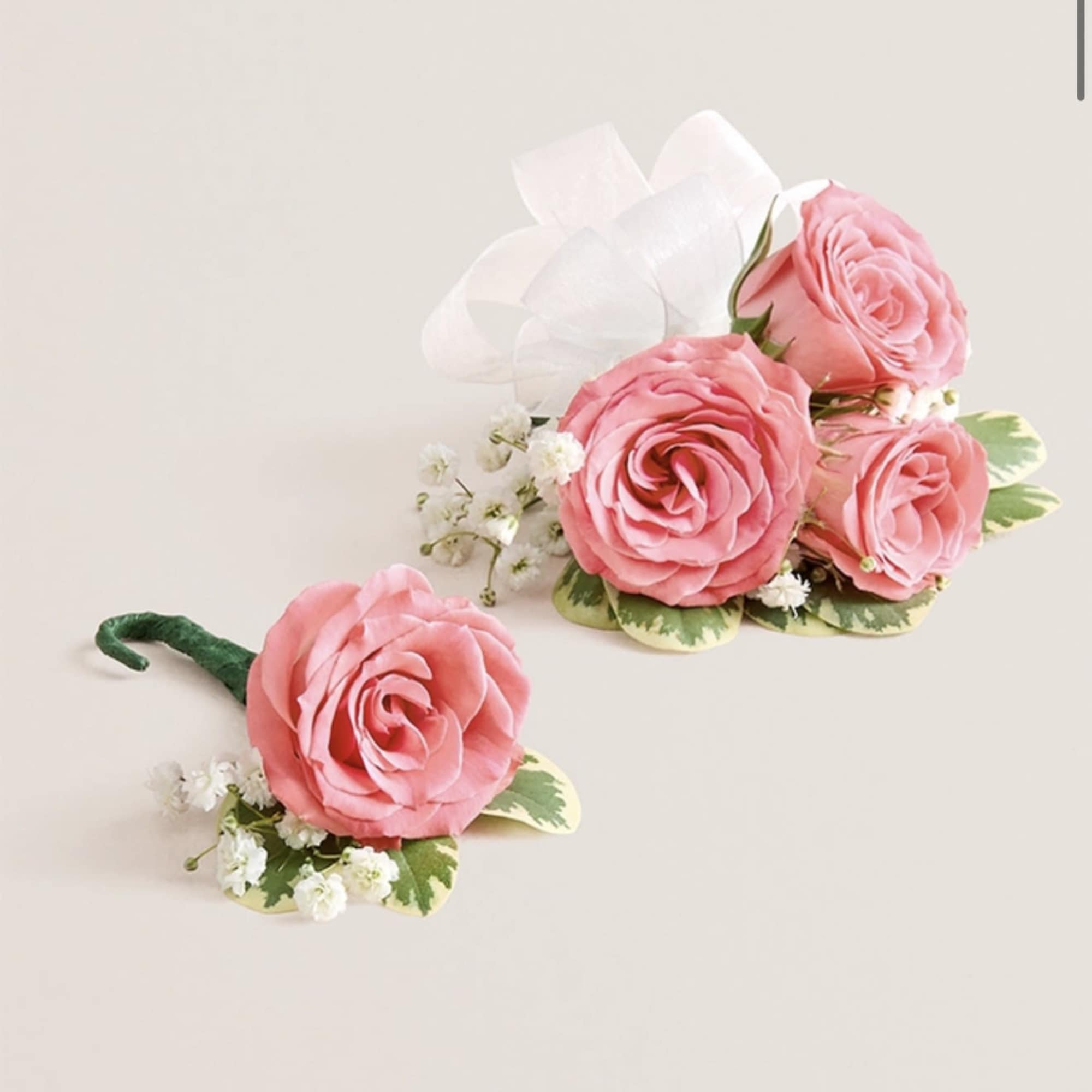 This striking corsage and boutonniere set, featuring delicate light pink blooms, is