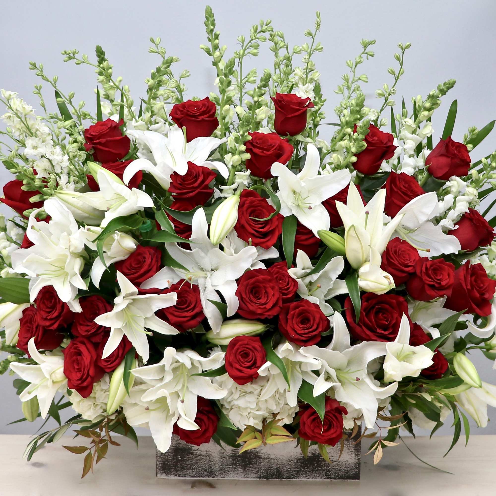 Large arrangement of red roses and white lilies in a rectangular container
