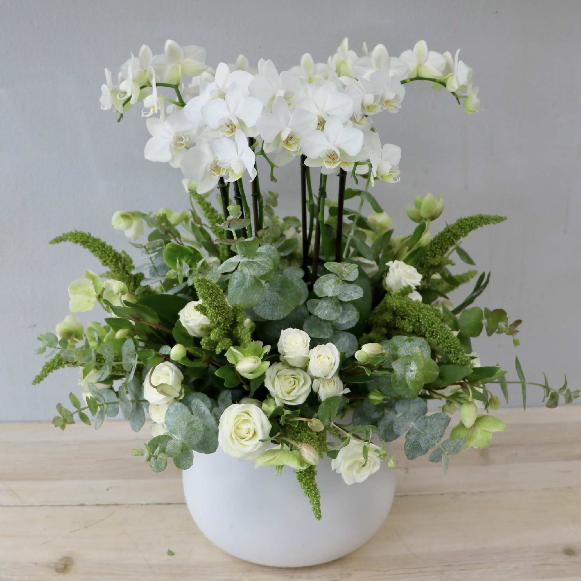 White orchids and roses arranged in a white vase