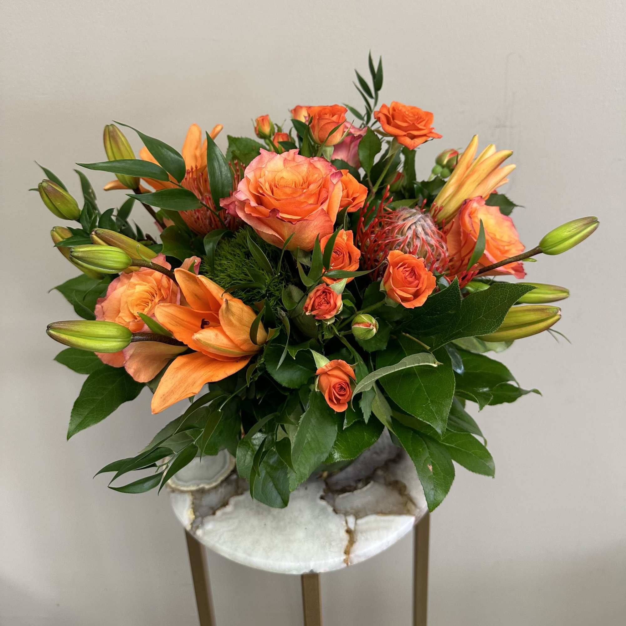A monochromatic mix of oranges that includes pin-cushion protea, free spirit roses