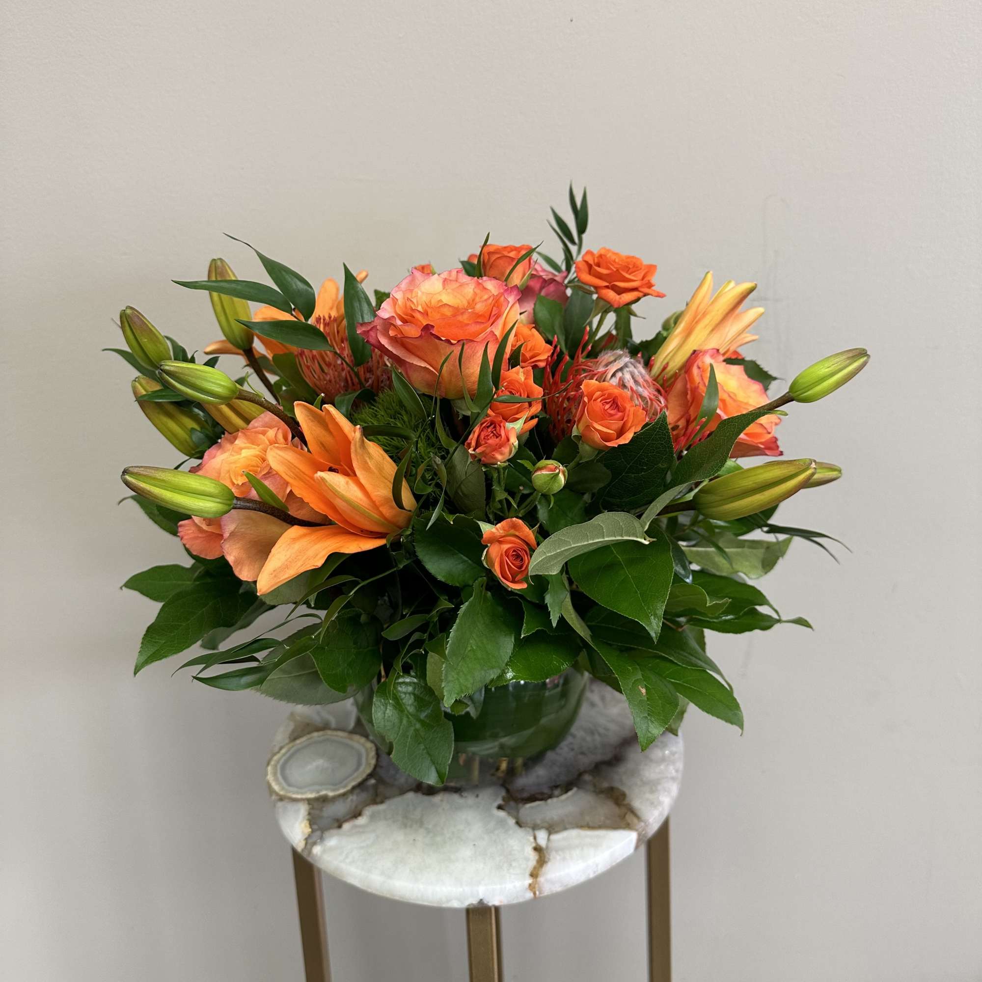 A monochromatic mix of oranges that includes pin-cushion protea, free spirit roses