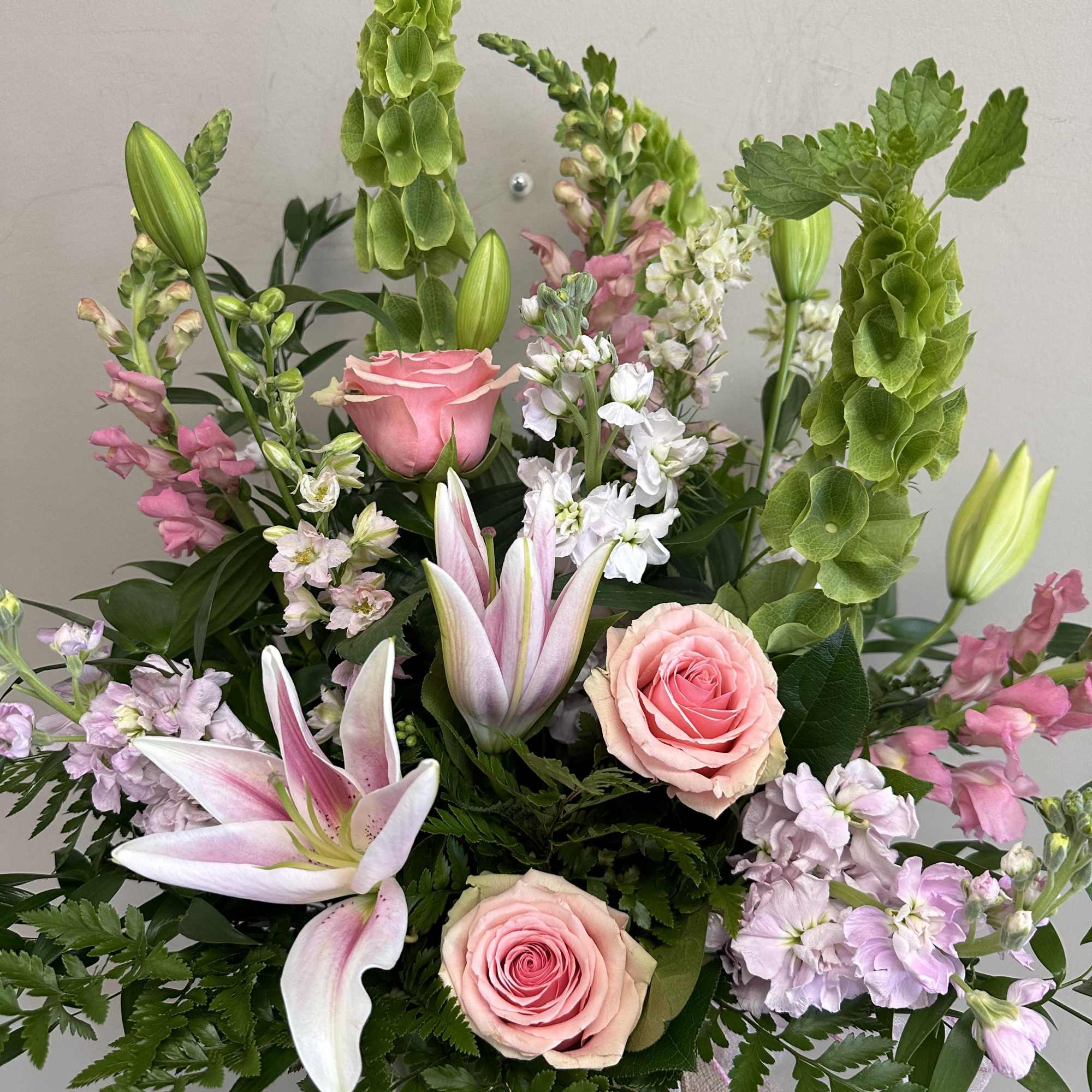 Pink roses and lilies with green bells of Ireland in a bouquet