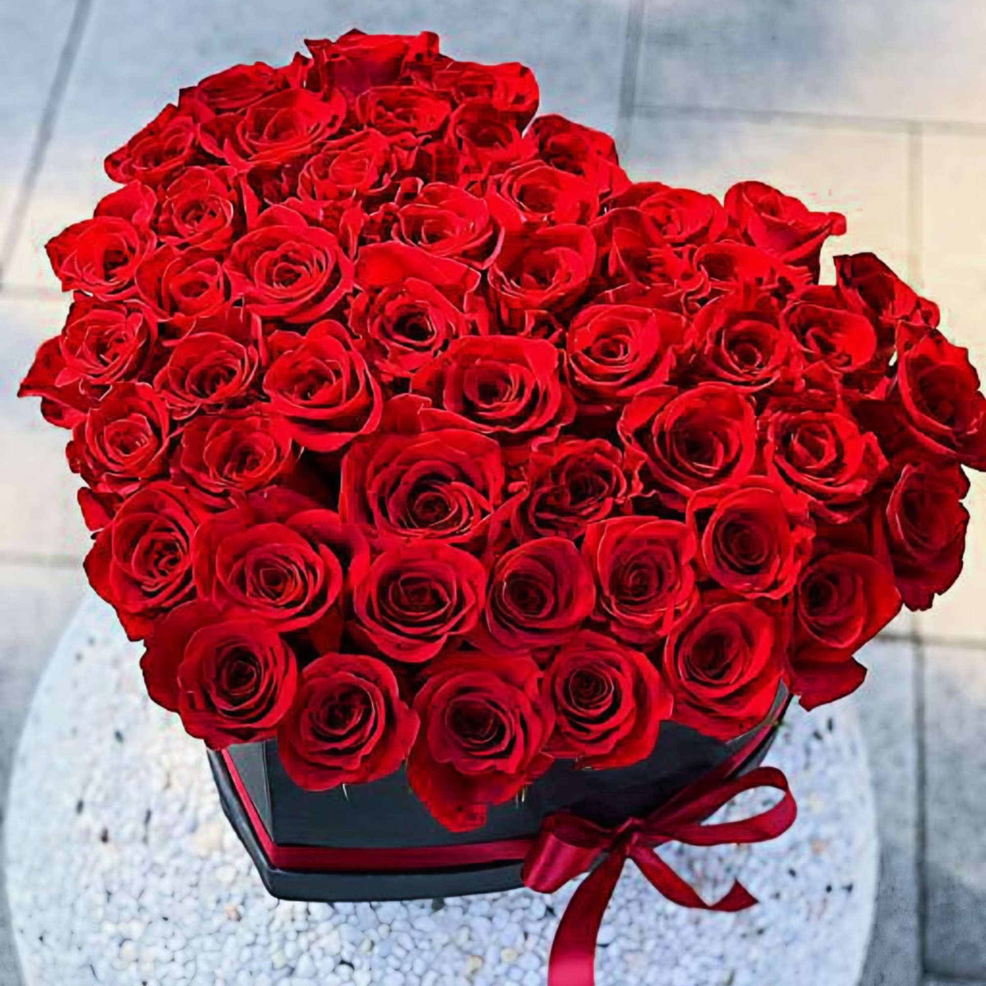 Large bouquet of red roses in a black box with a red ribbon