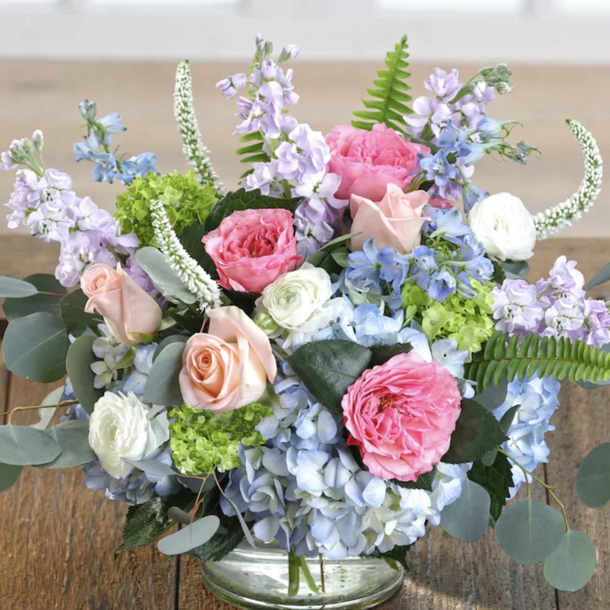 Pastel floral arrangement in a clear glass vase with roses and hydrangeas