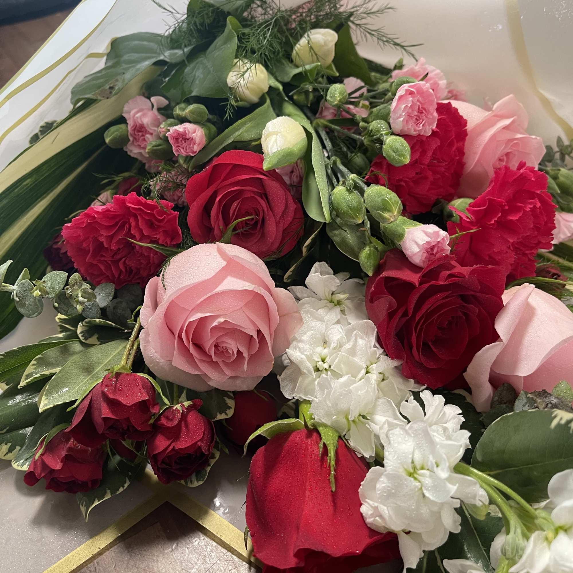 Bouquet of pink and red roses with white flowers in white wrap