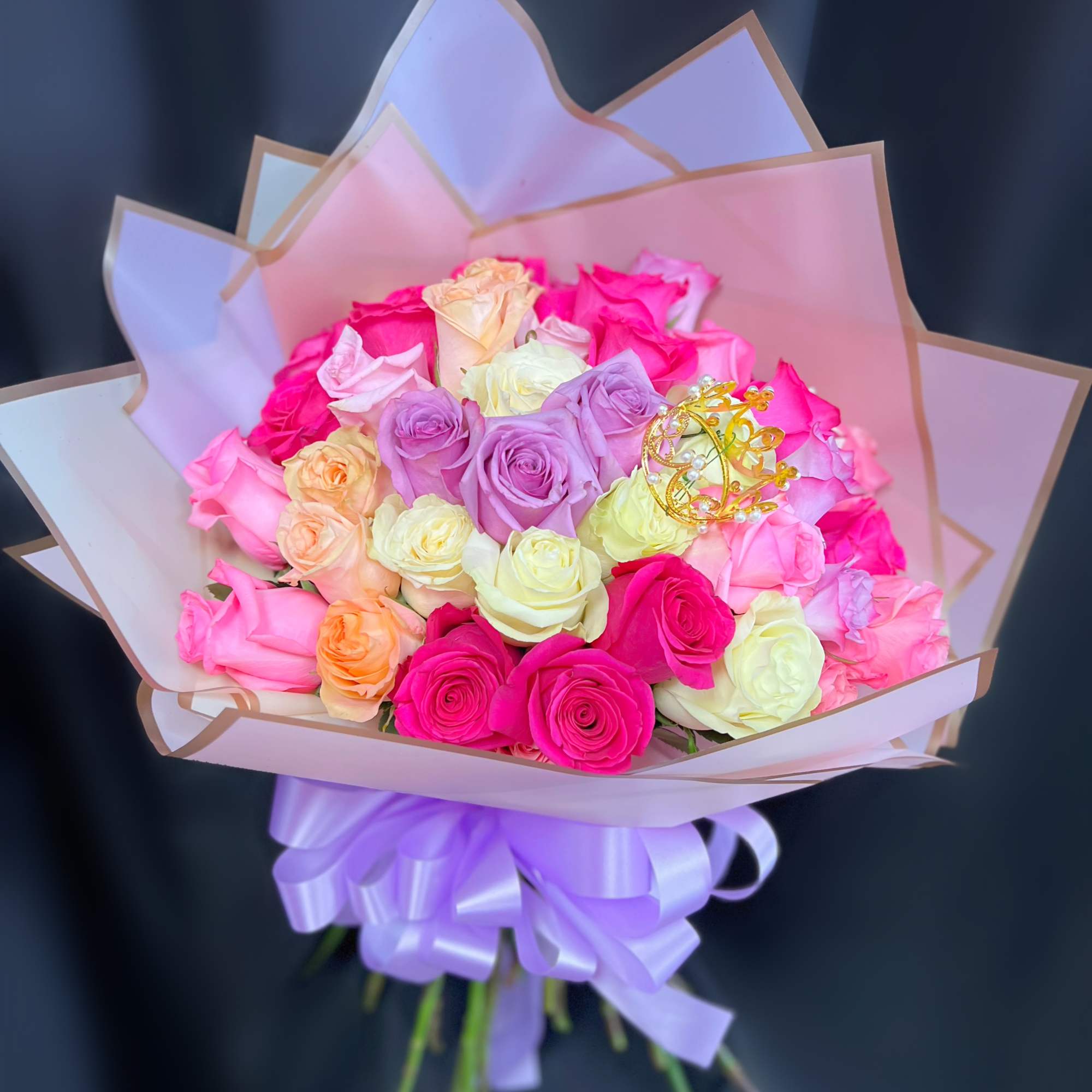 Bouquet of multicolored roses wrapped in pastel paper with a lavender ribbon
