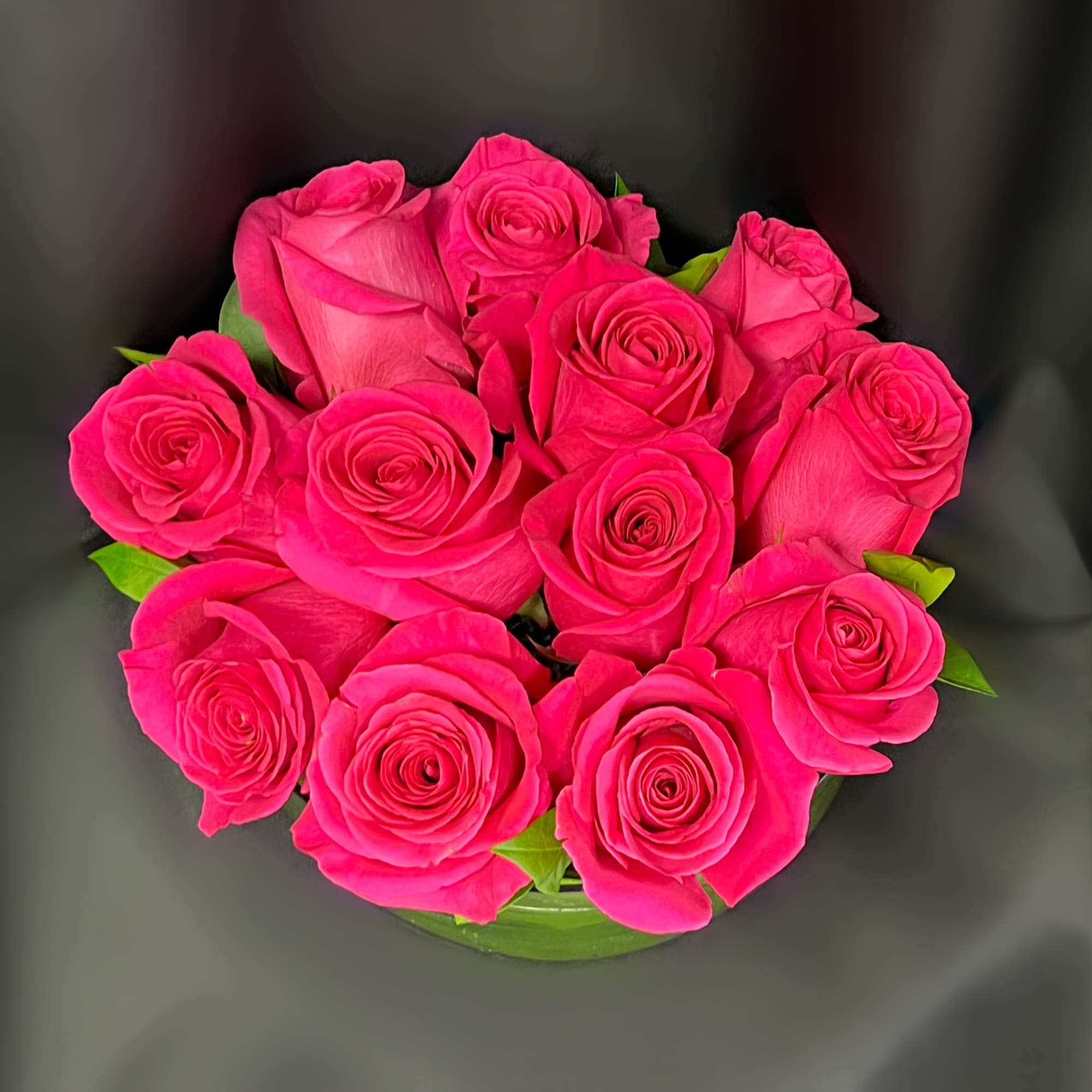 Bouquet of bright pink roses with a few green leaves