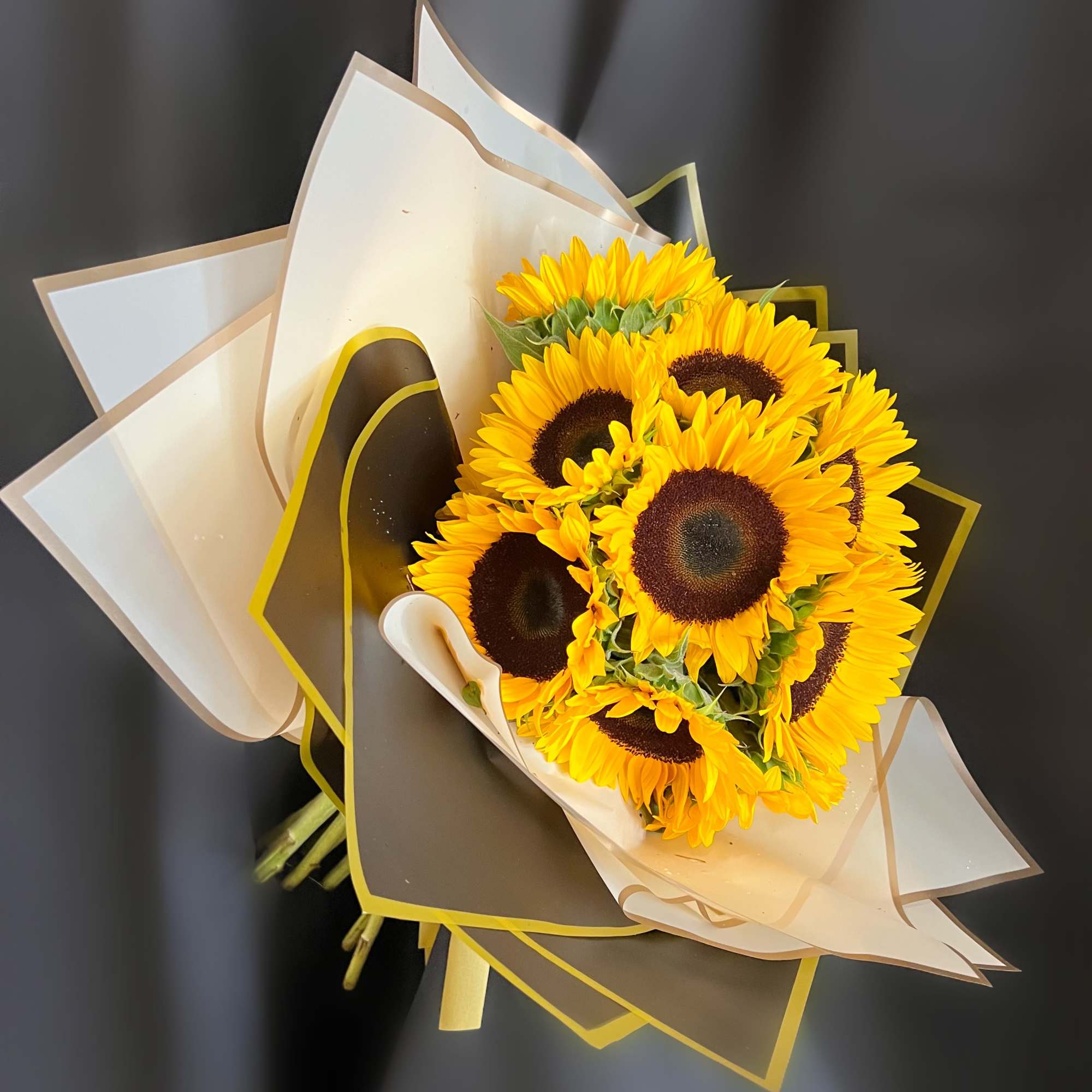 Bouquet of bright yellow sunflowers wrapped in white and black paper