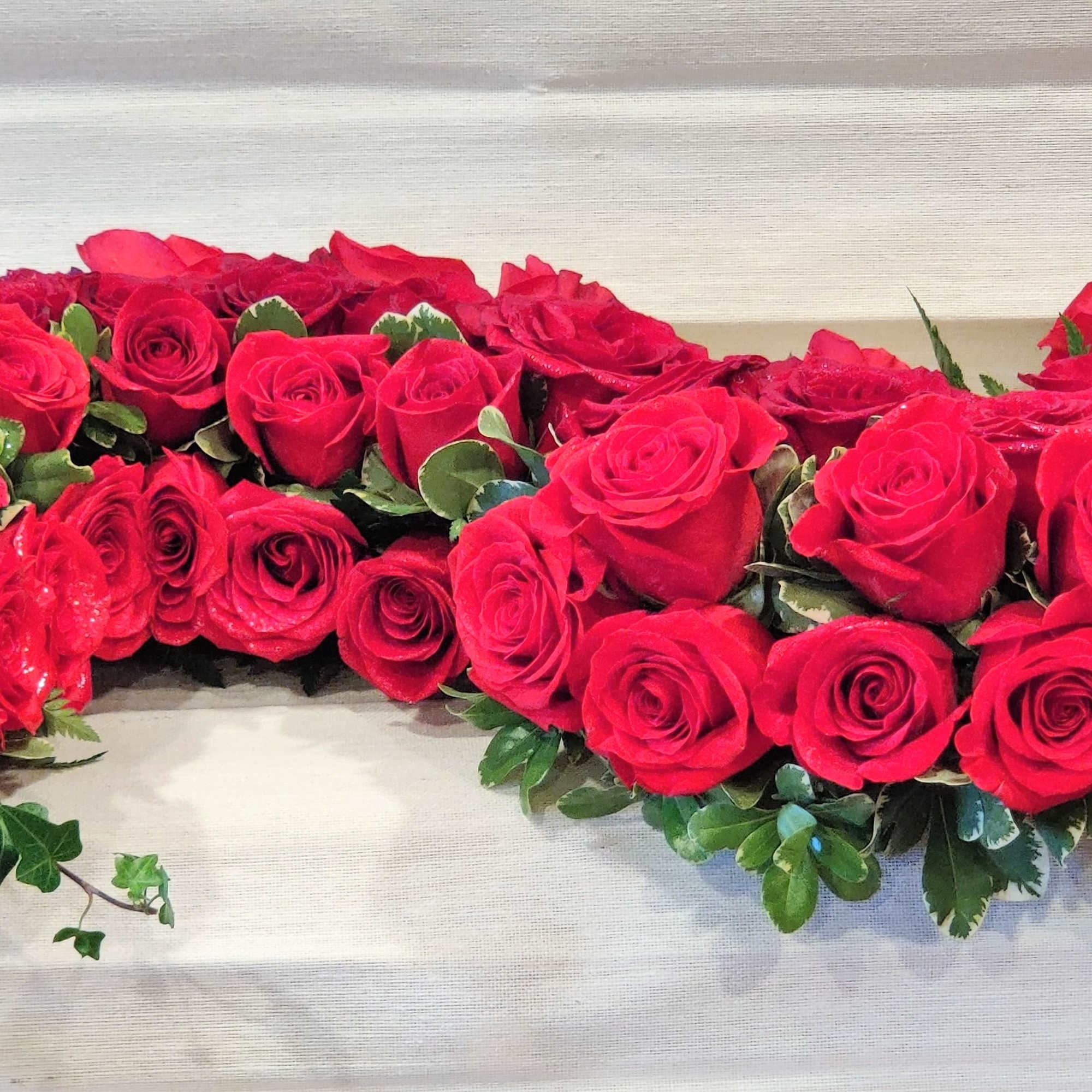 Heart-shaped arrangement of red roses with green foliage