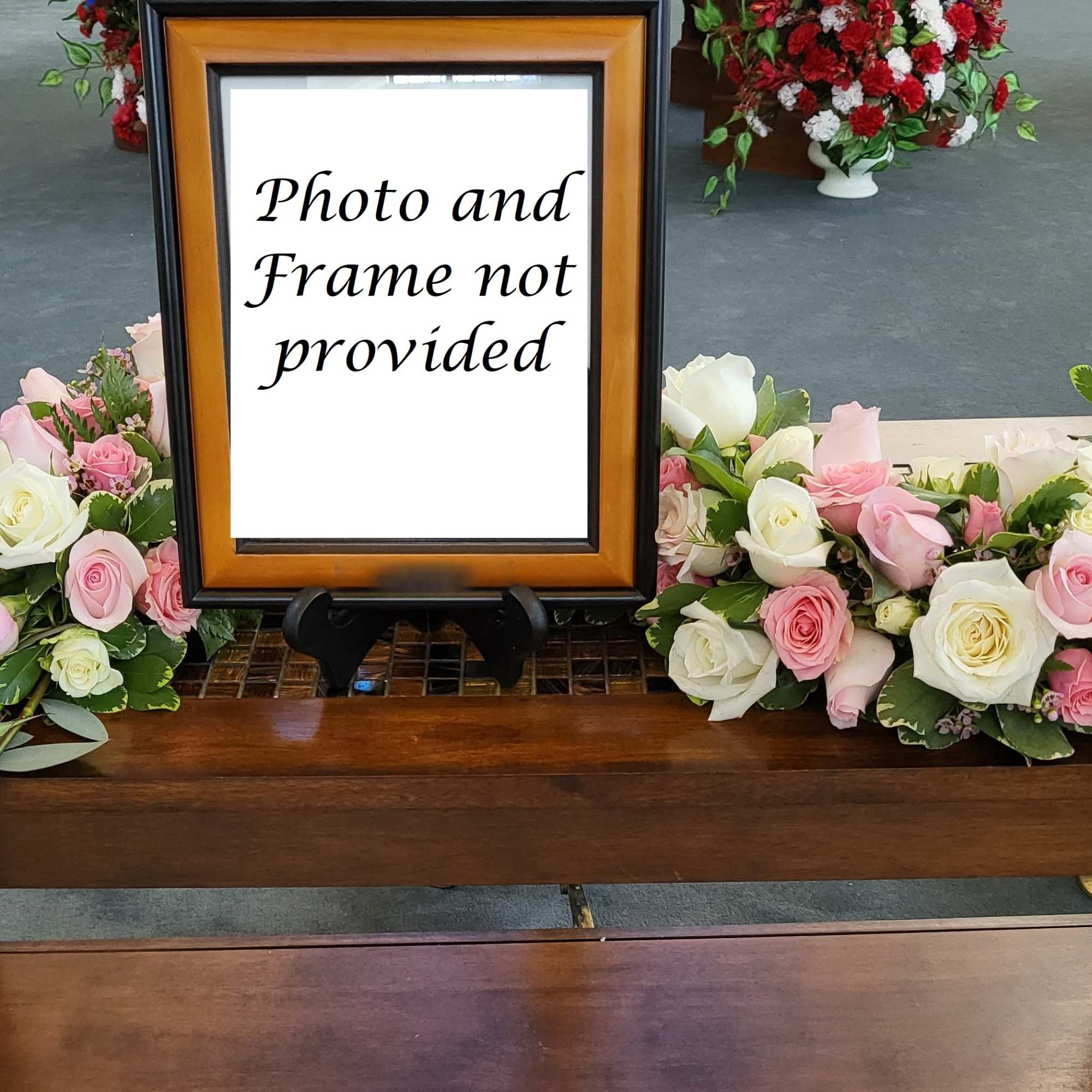 Pink and white rose arrangements flank a framed sign on a wooden table.