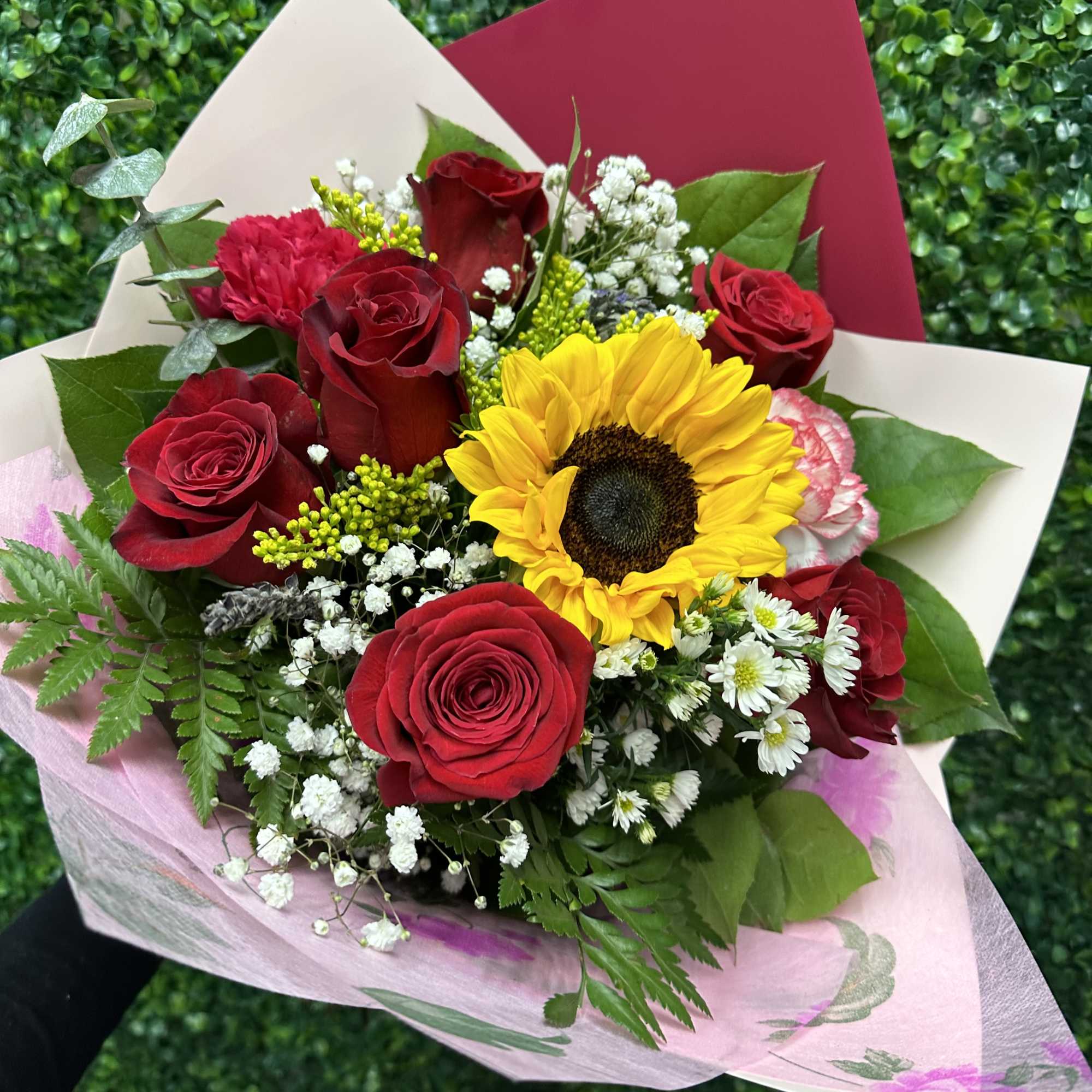 Bouquet of red roses and a sunflower wrapped in pink paper
