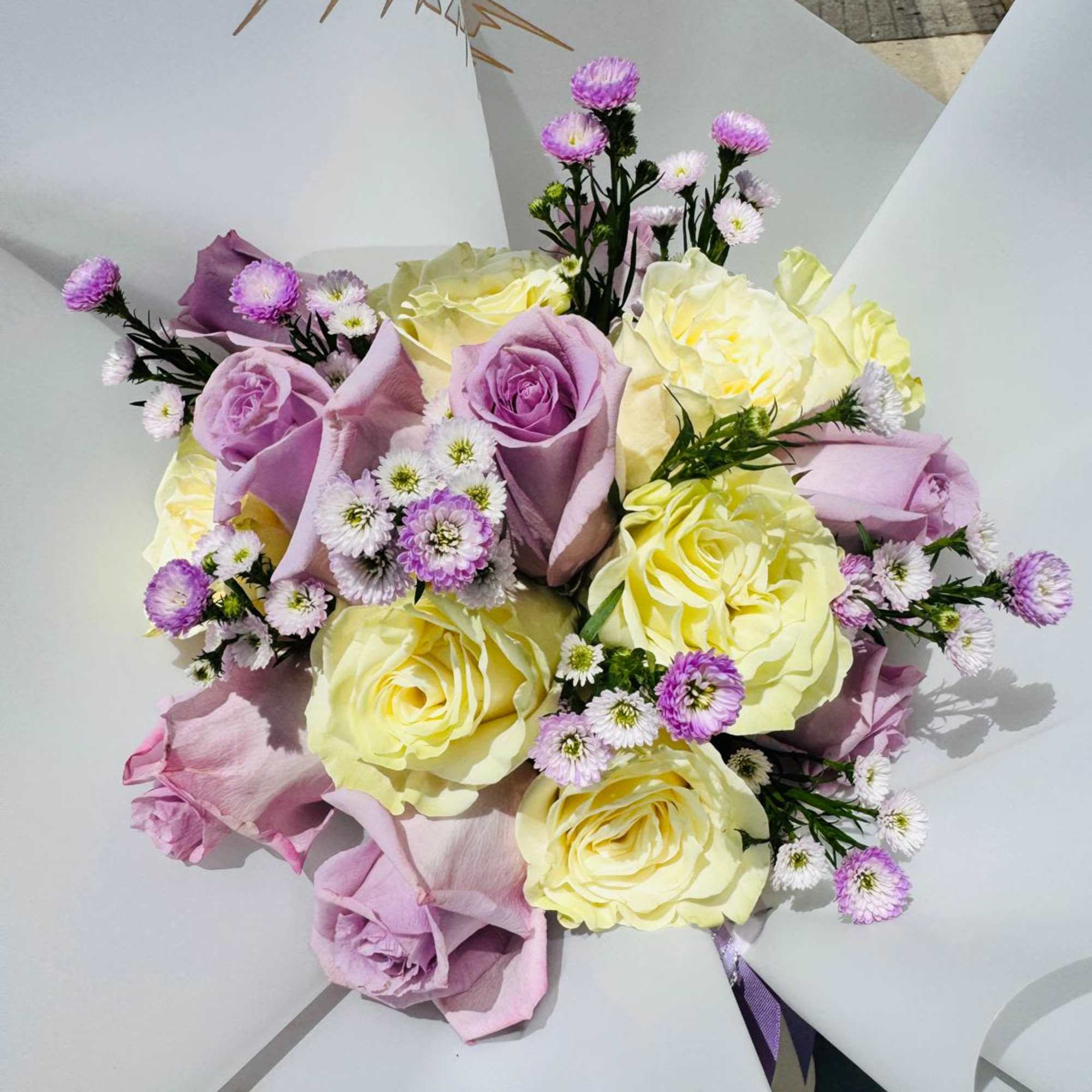 Bouquet of lavender and pale yellow roses with small purple filler flowers