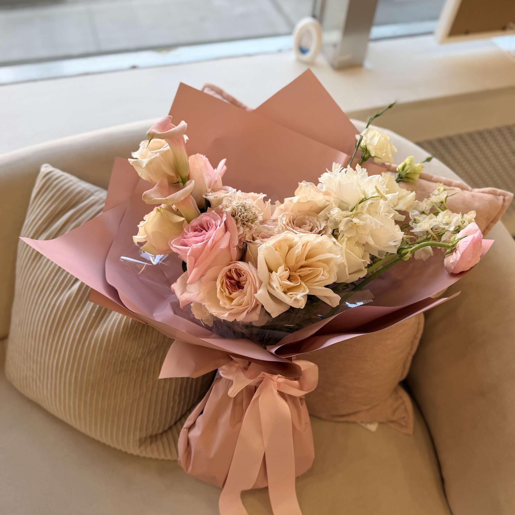 A lush, hand-tied bouquet in soft pinks, peach, cream and a touch