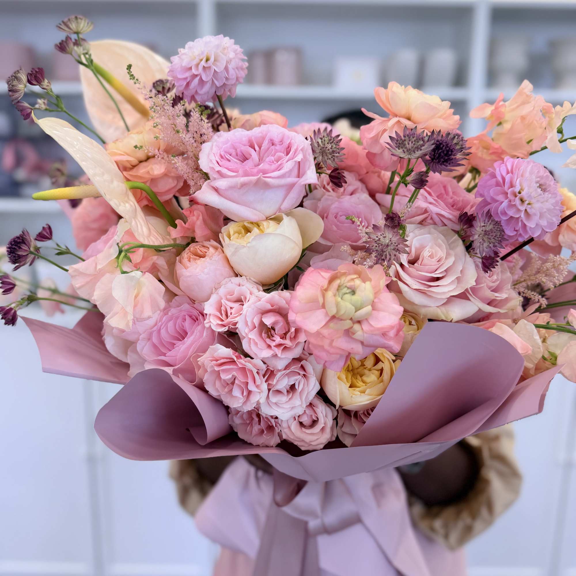 A lush, hand-tied bouquet in soft pinks, peach, cream and a touch