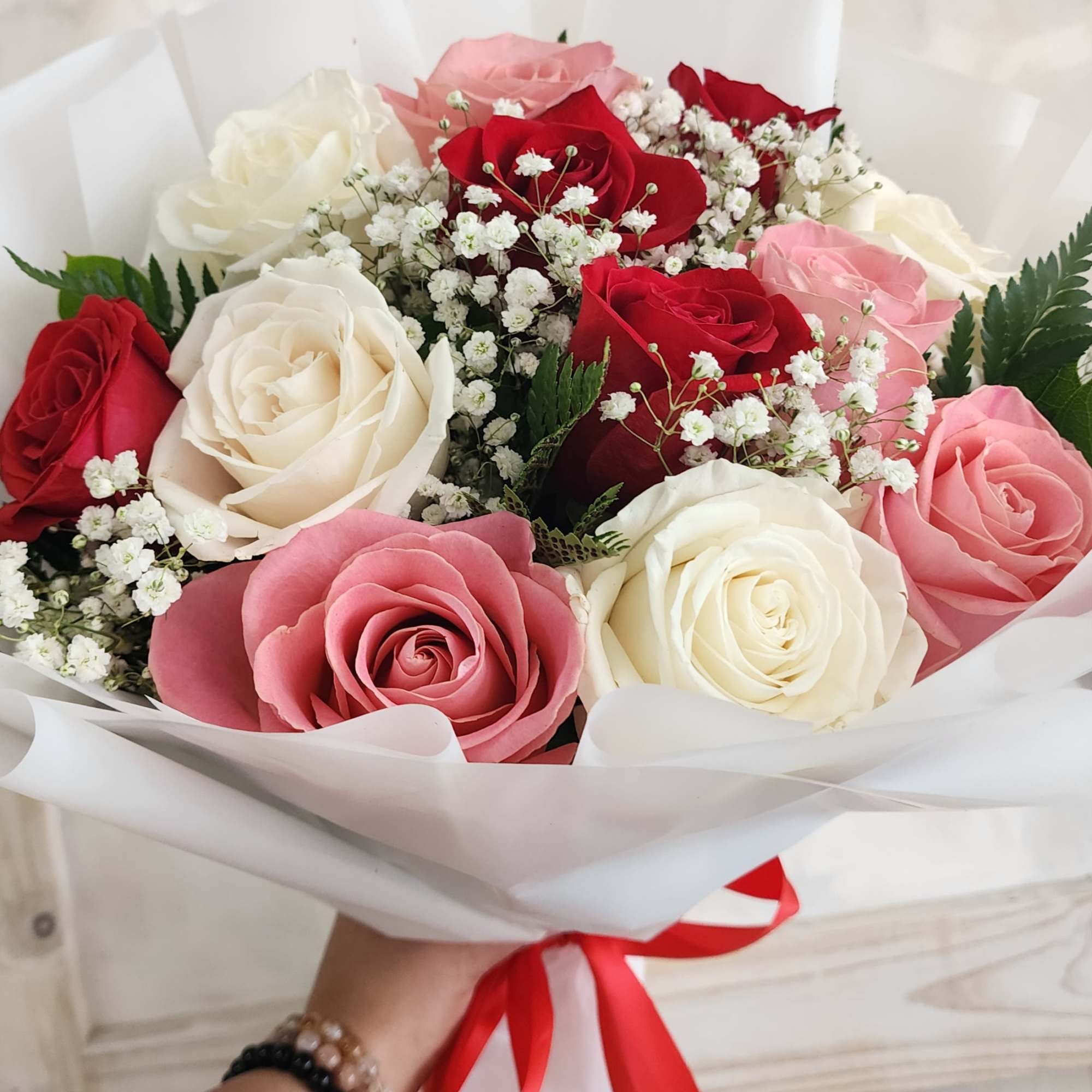 Bouquet of red, pink, and white roses with baby's breath in white wrap