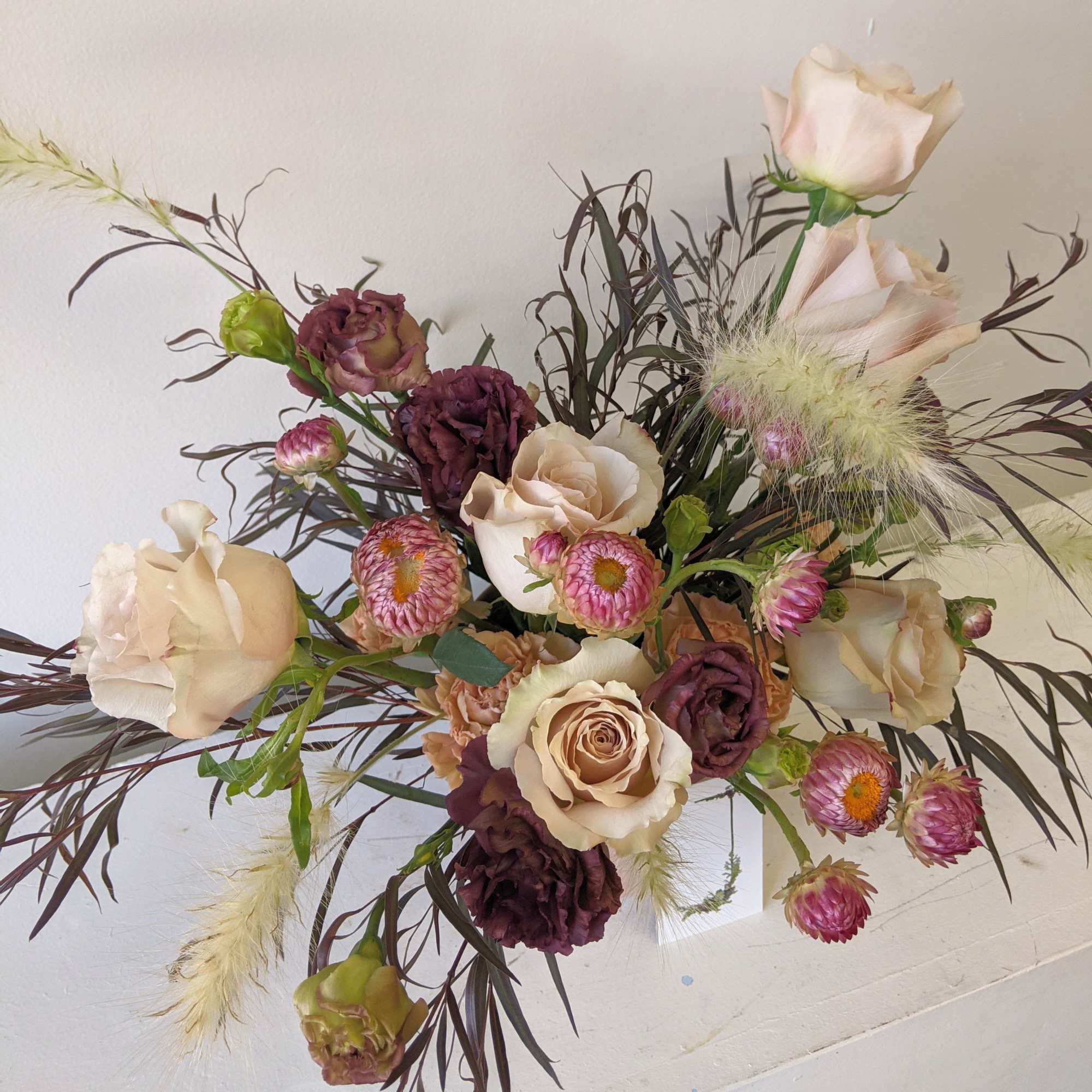 Loose bouquet of cream and burgundy roses with pink strawflowers