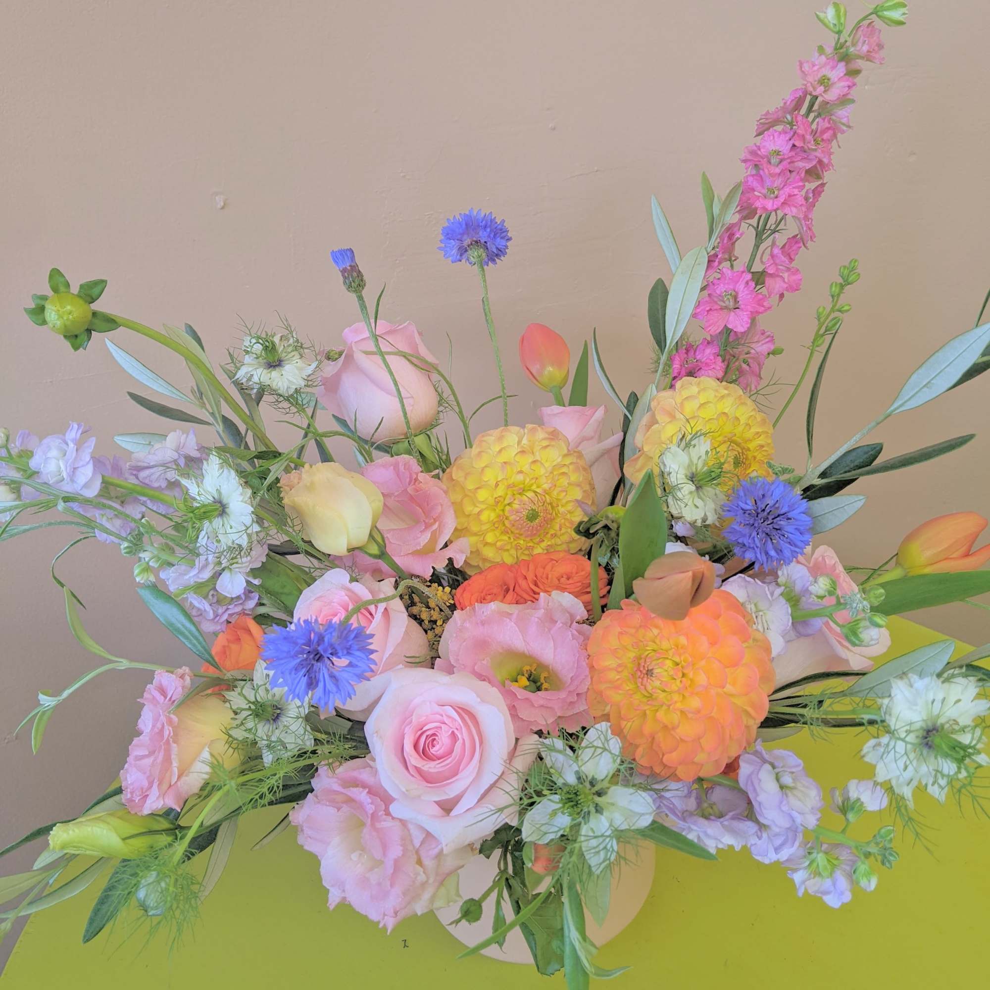 Pastel bouquet with pink roses, orange dahlias, and blue accent flowers