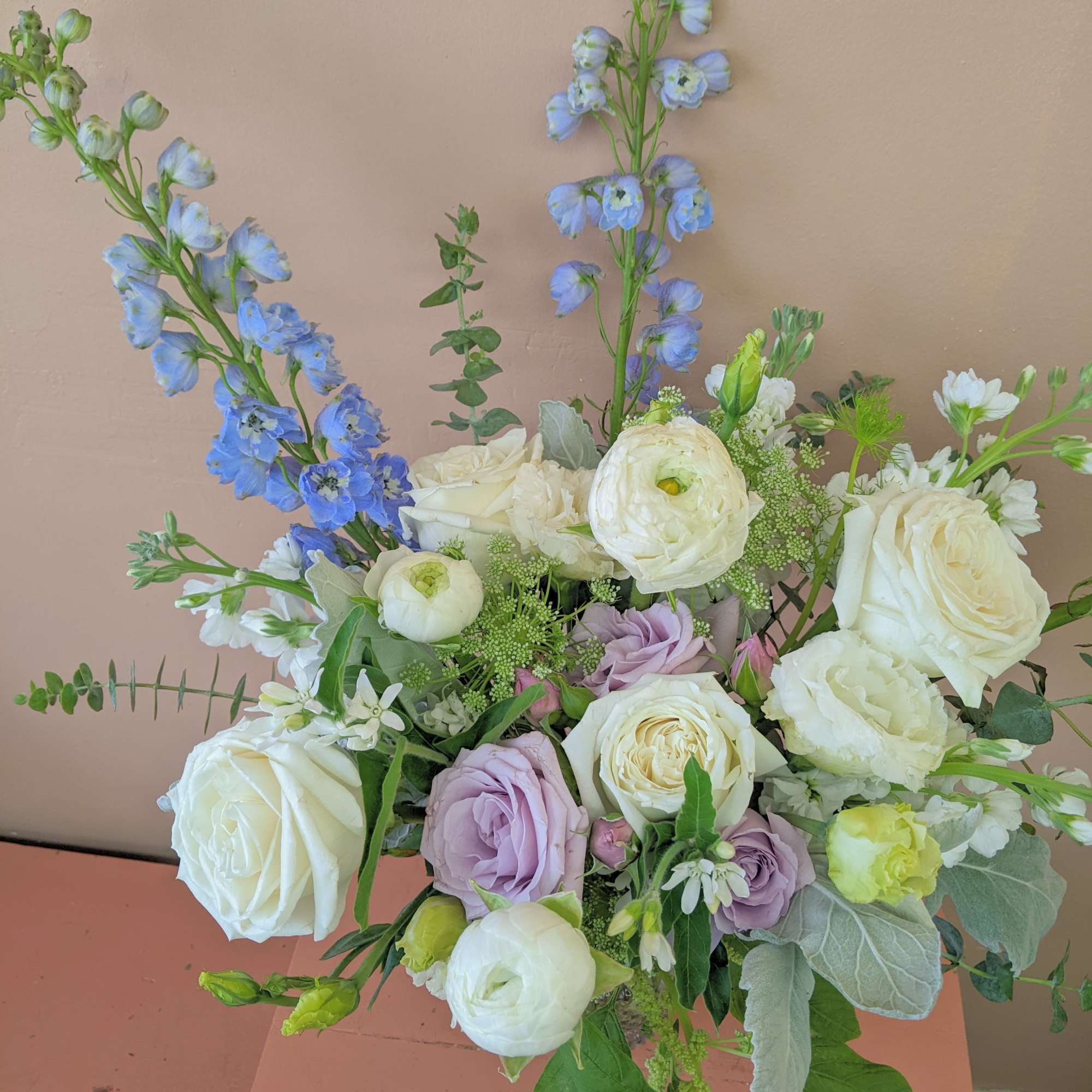 Bouquet of white and lavender roses with tall blue delphinium