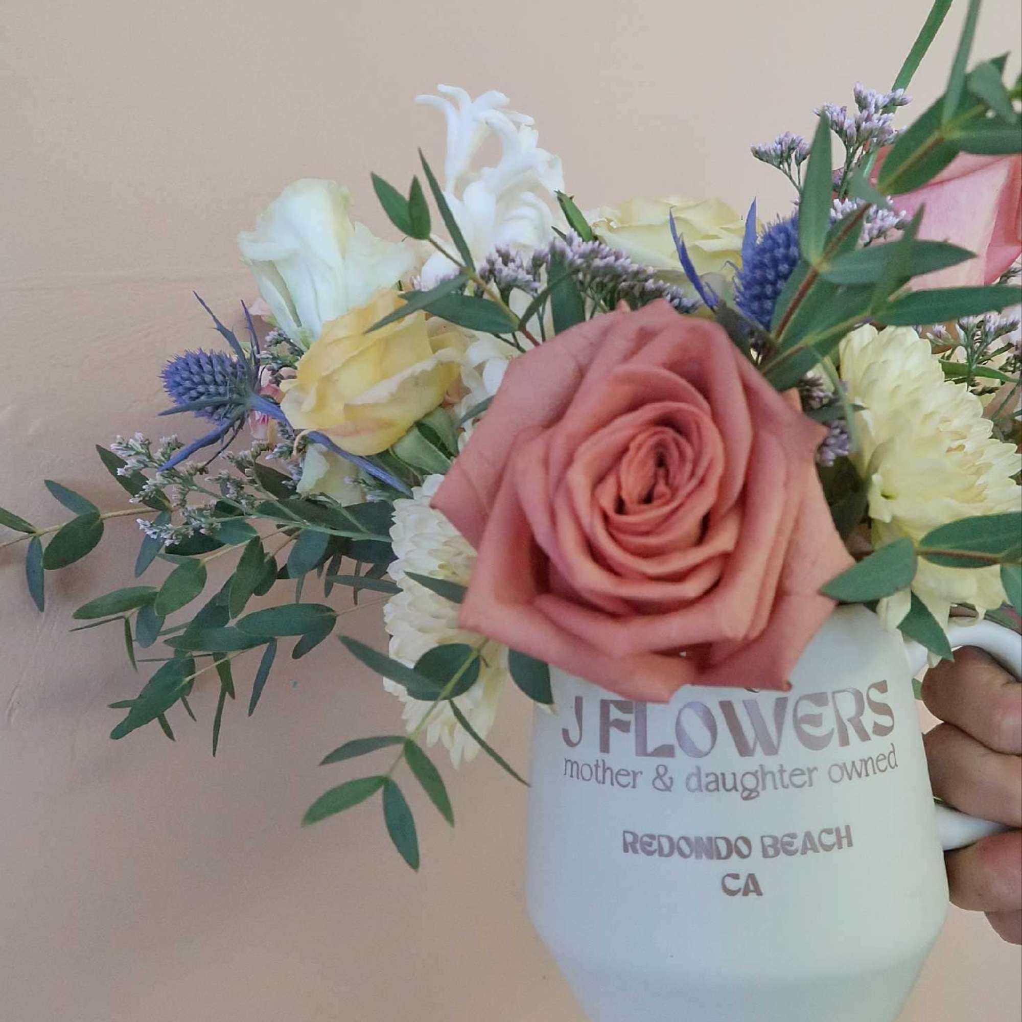 Mixed bouquet with a pink rose in a white mug vase