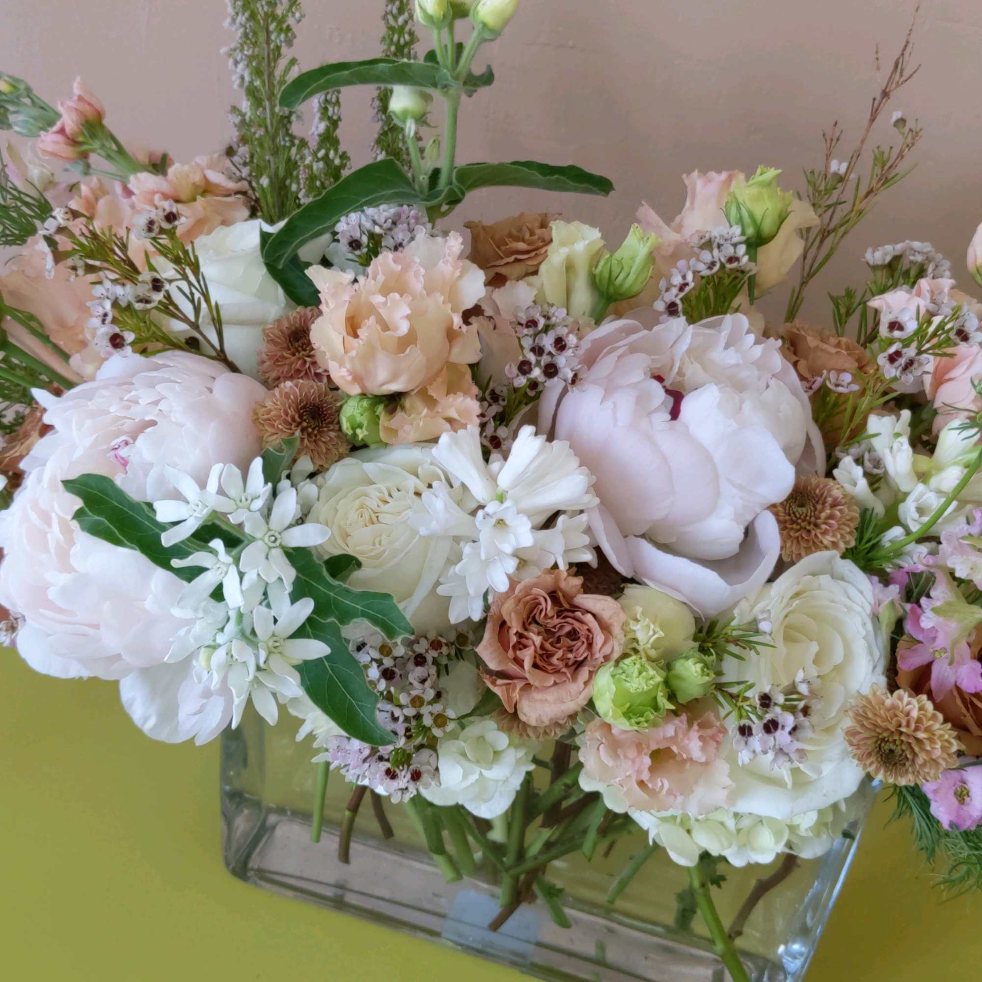 Pastel floral arrangement in a clear rectangular vase