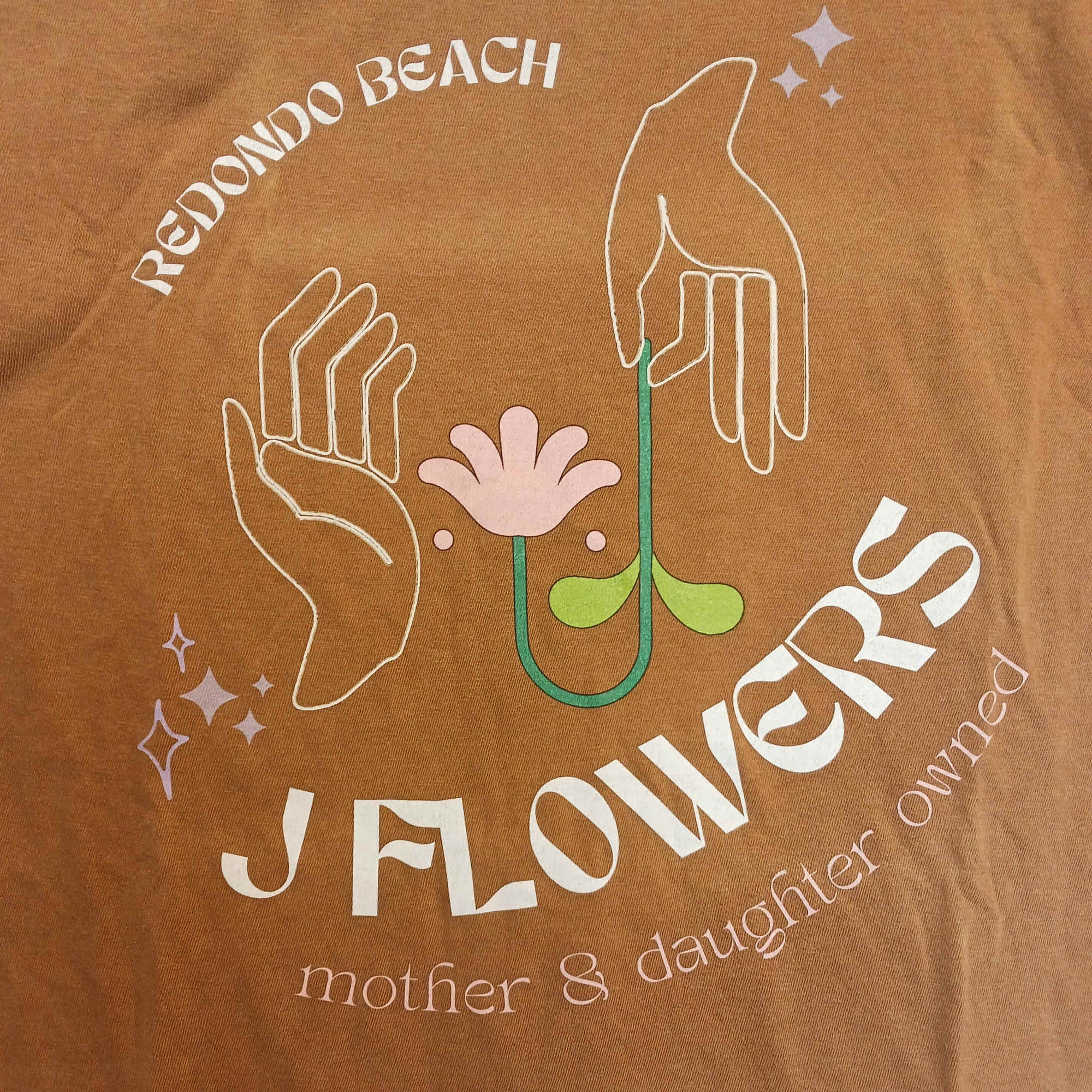 Brown T-shirt with a floral graphic and the words "Redondo Beach Flowers"