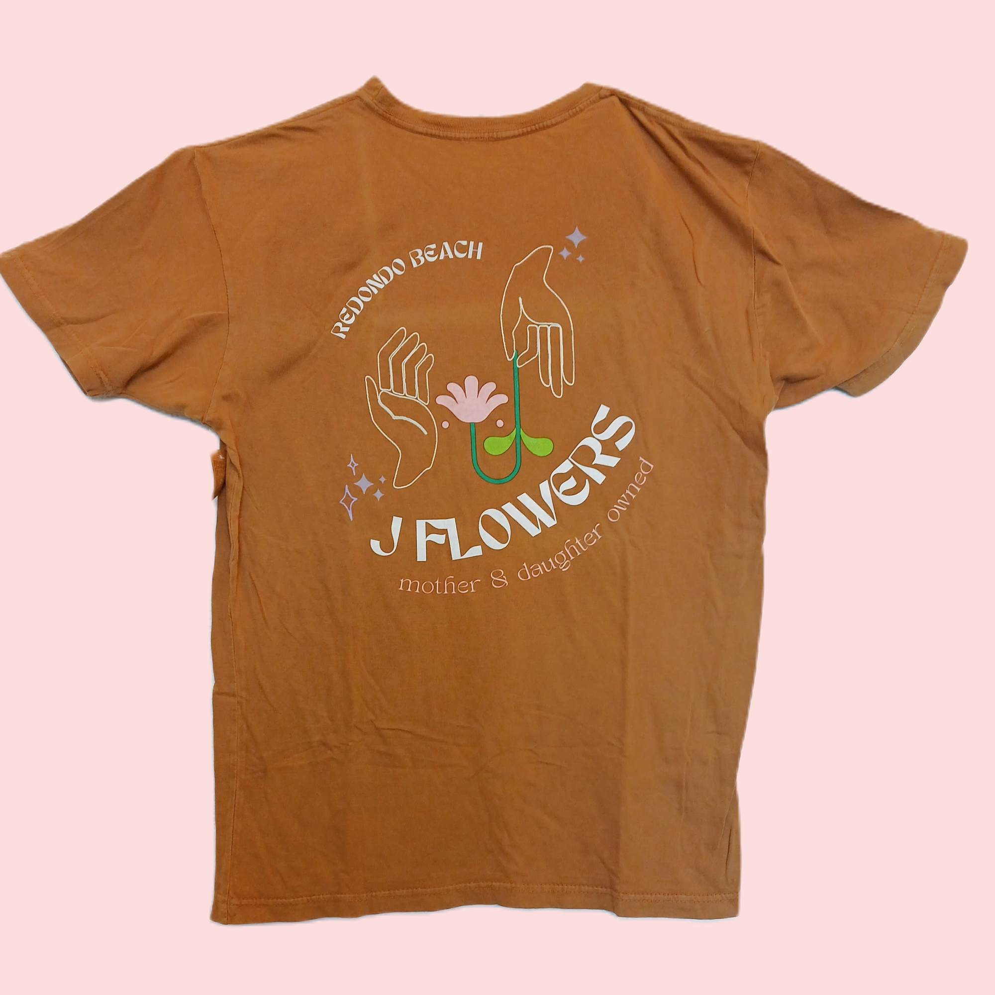 Brown graphic T-shirt with a floral hand illustration and text