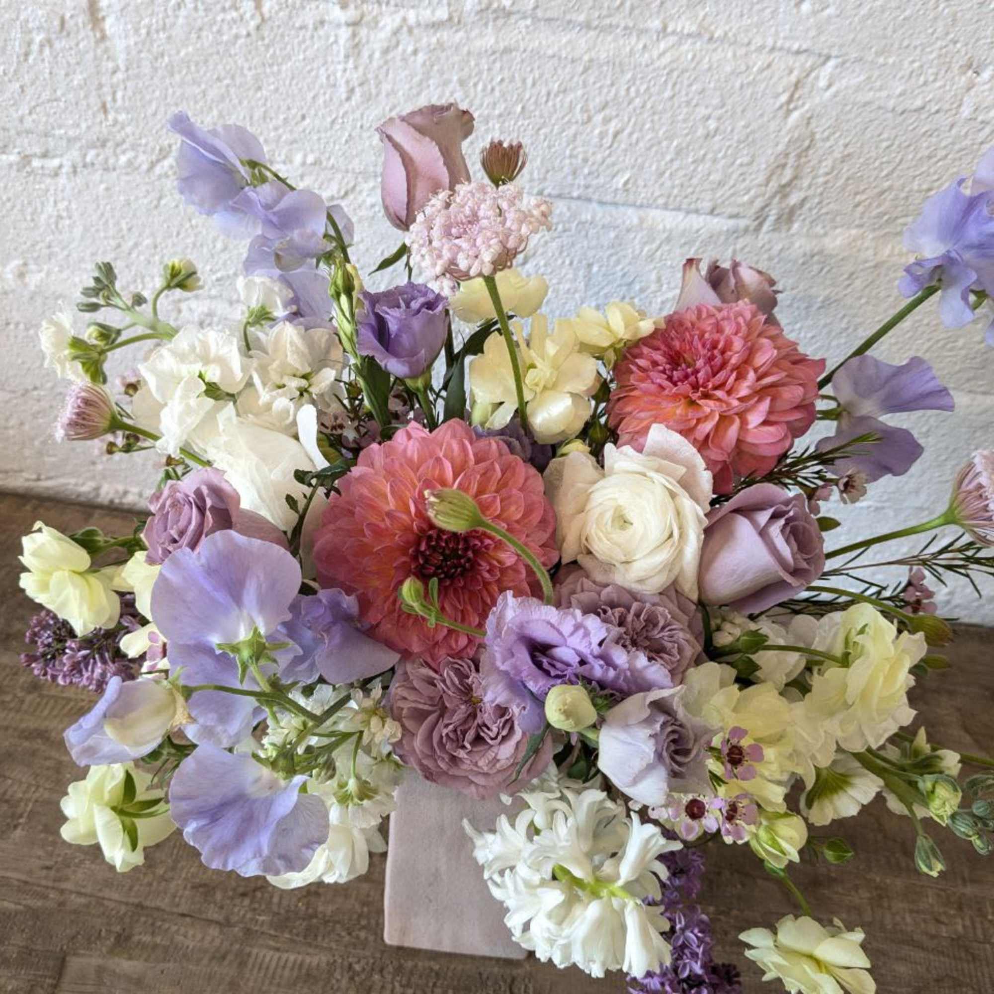 Pastel bouquet of pink, lavender, and white flowers in a square vase