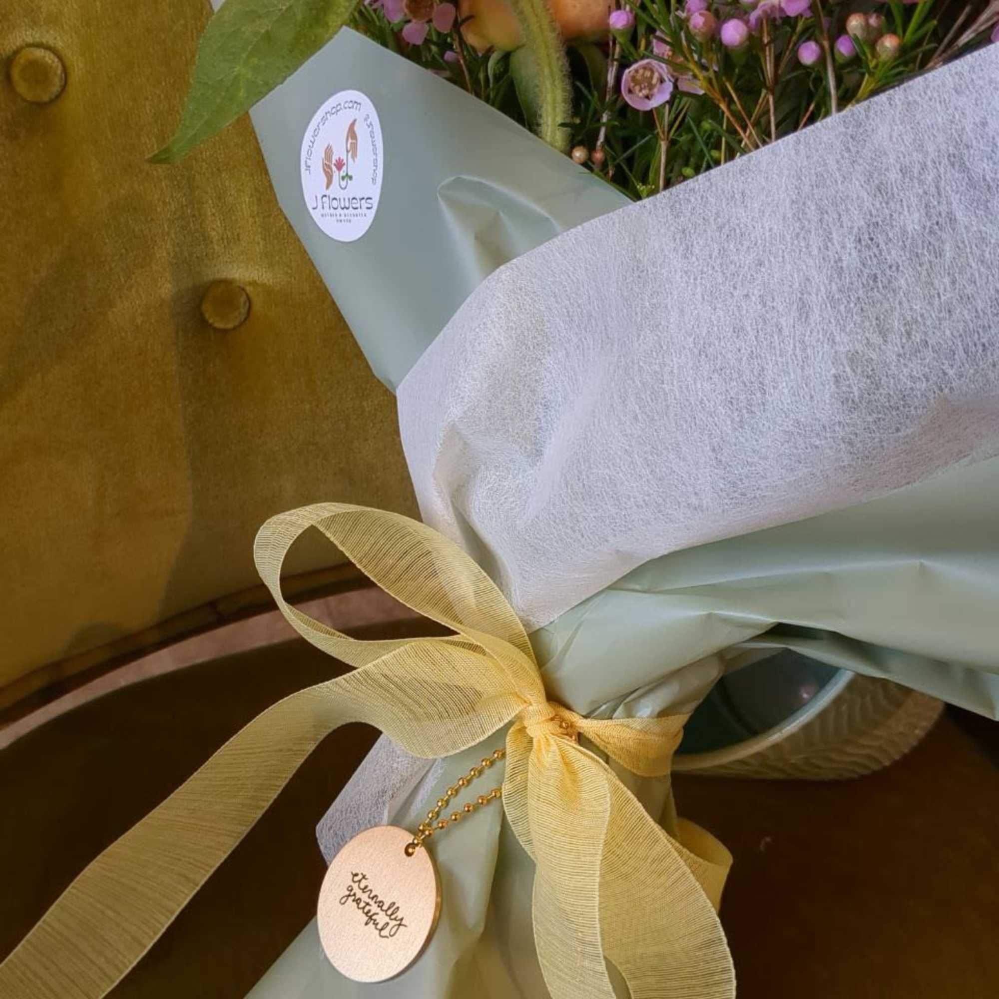 Pink bouquet wrapped in pale paper with a yellow ribbon