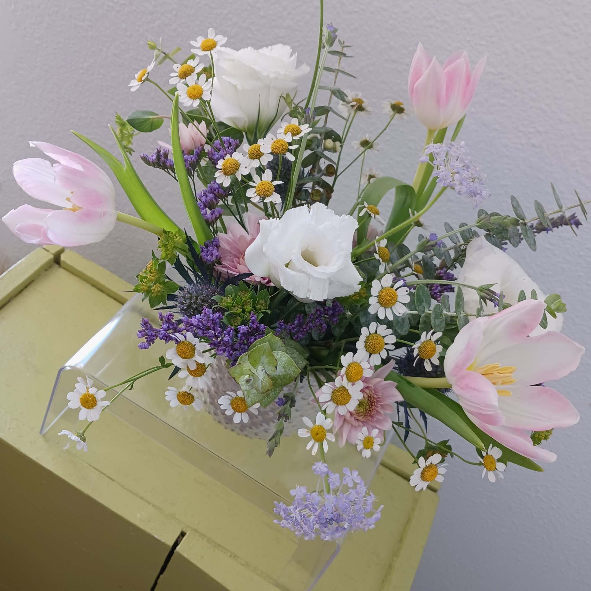 Mixed bouquet with pink tulips, white blooms, and small daisy flowers in a clear vase