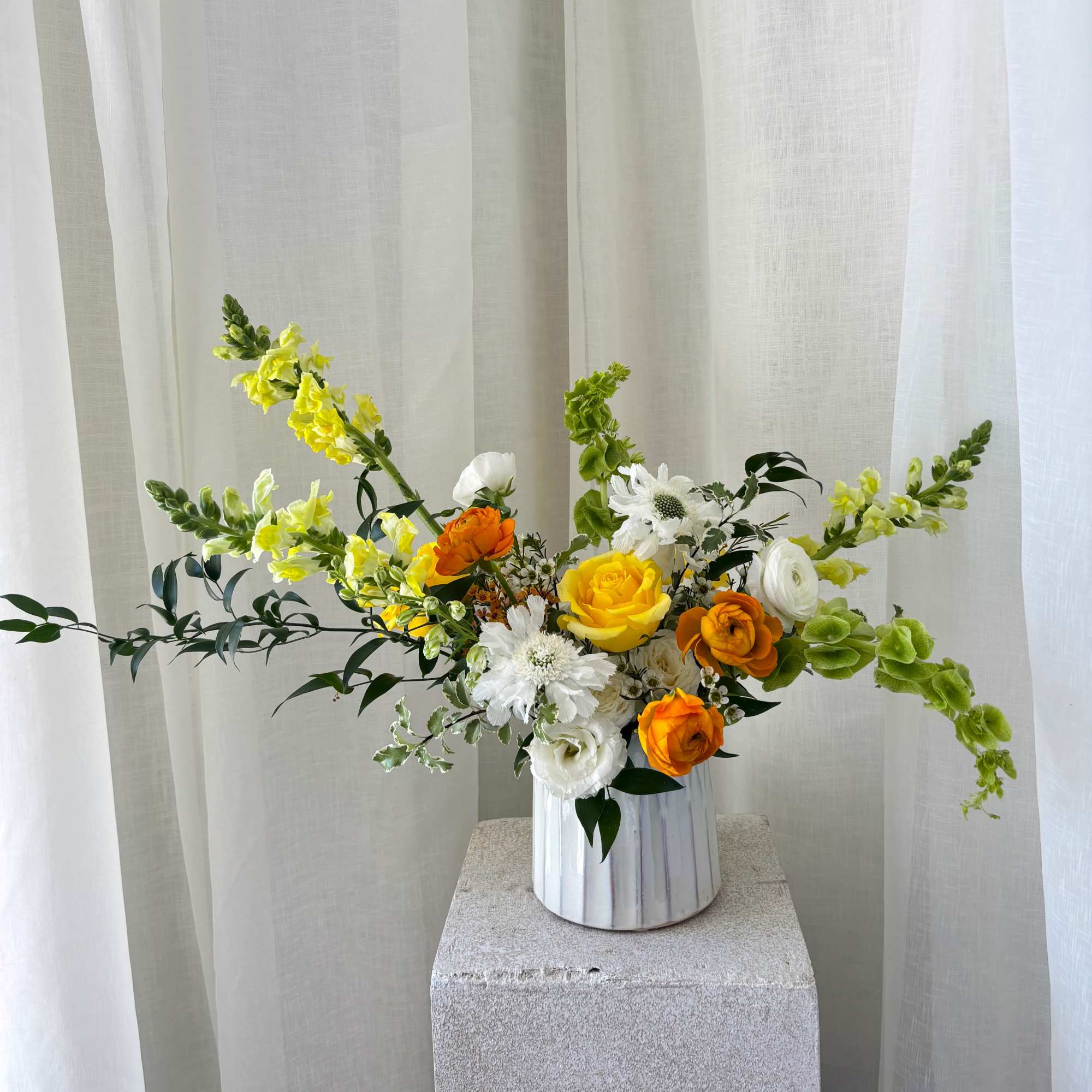 Yellow, white, and orange flowers in a white vase