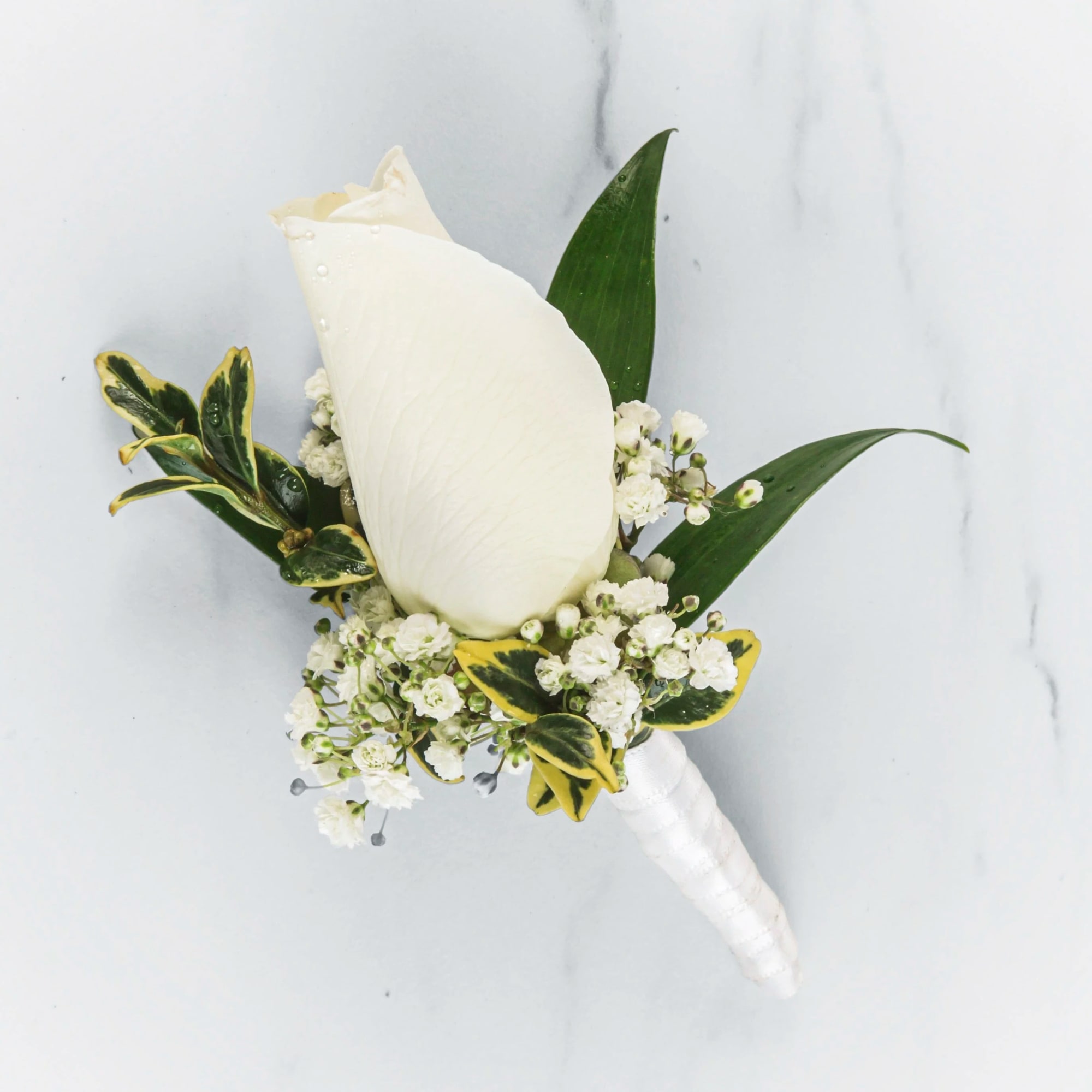 White calla lily boutonniere with small white flowers and variegated leaves