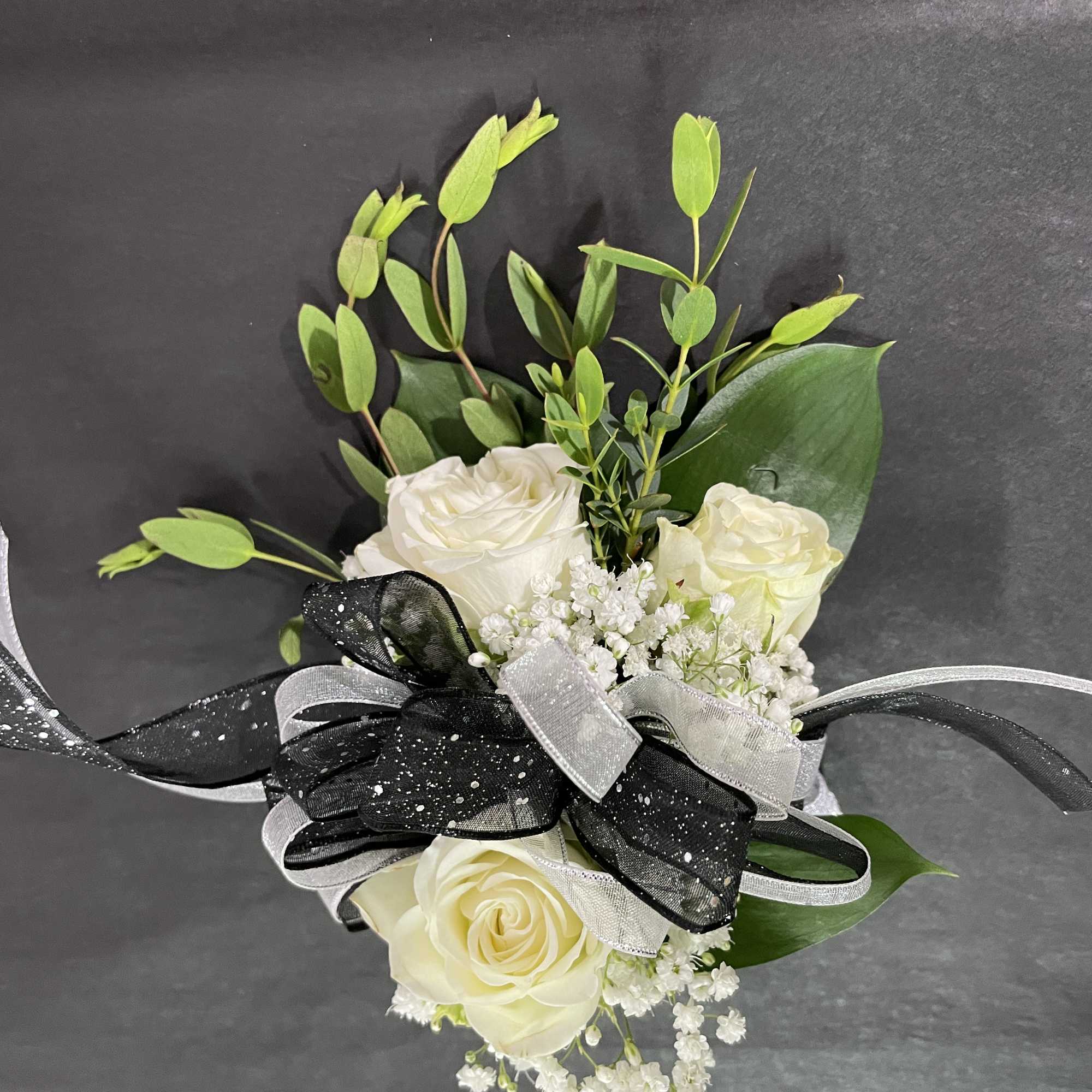 White rose bouquet with black and silver ribbon on a dark background