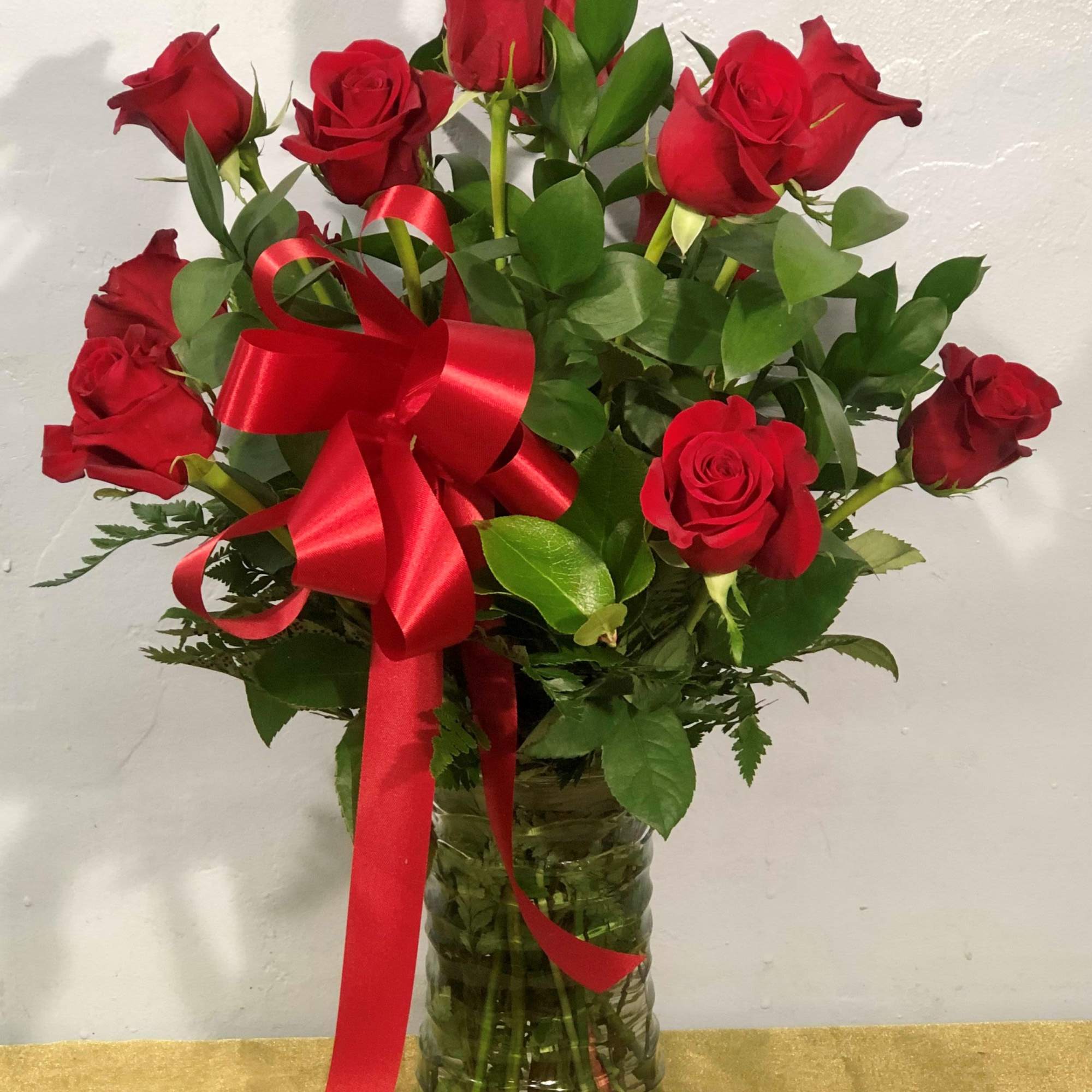 A dozen long-stemmed red roses gathered in a tall clear glass vase, photo 2 of 2