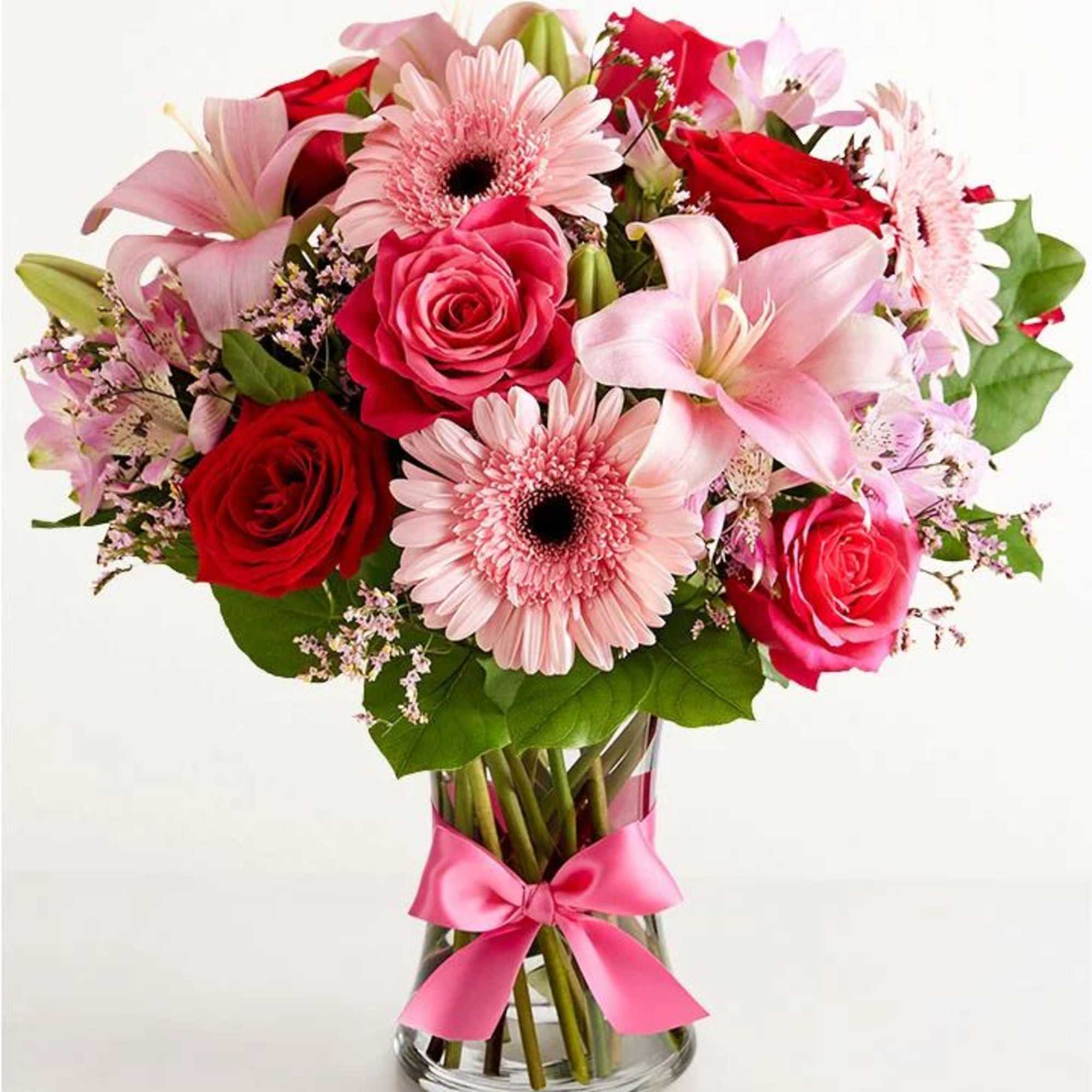 Pink and red mixed bouquet in a glass vase with a pink ribbon