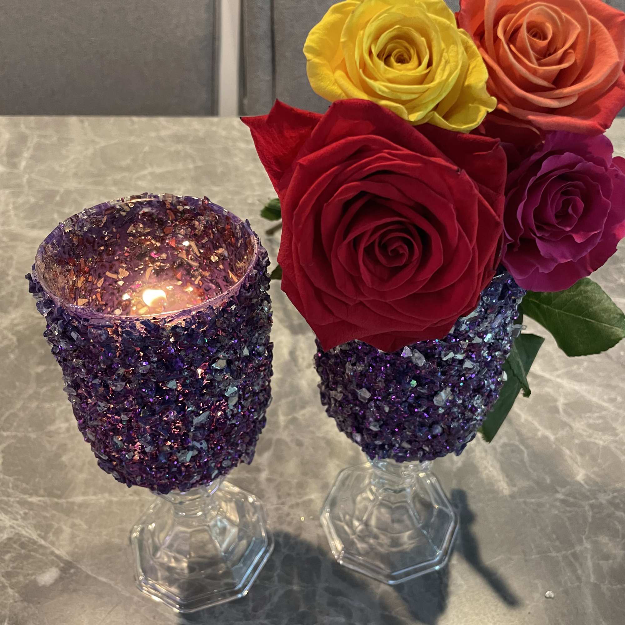 Two glitter-covered candle holders and a rose arrangement in glass goblets