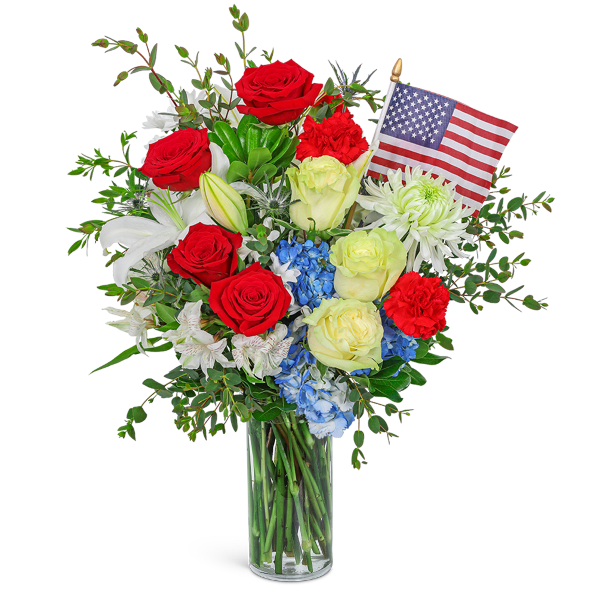 Red and white roses with lilies and a small American flag in a glass vase