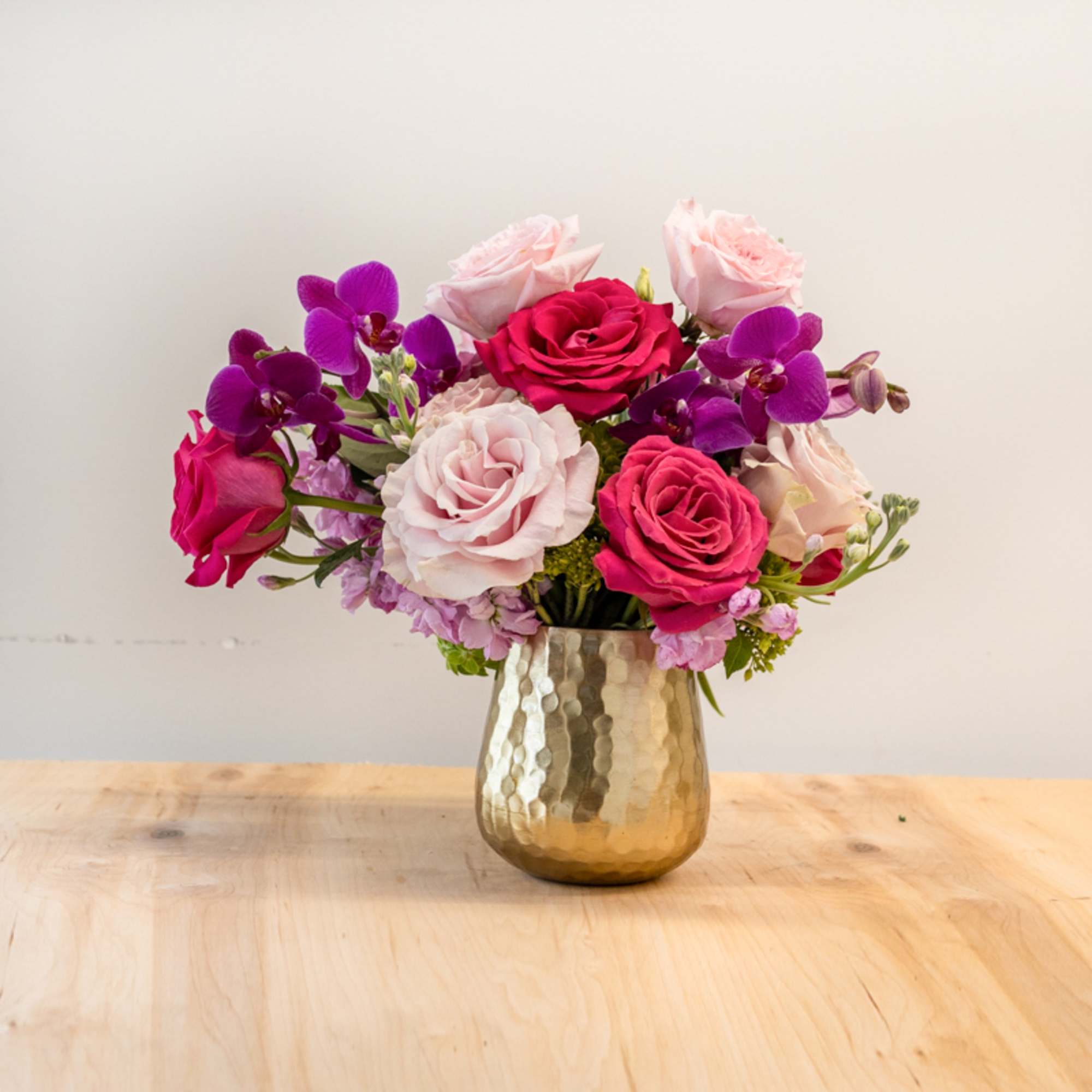 Pink and purple rose bouquet in a gold vase