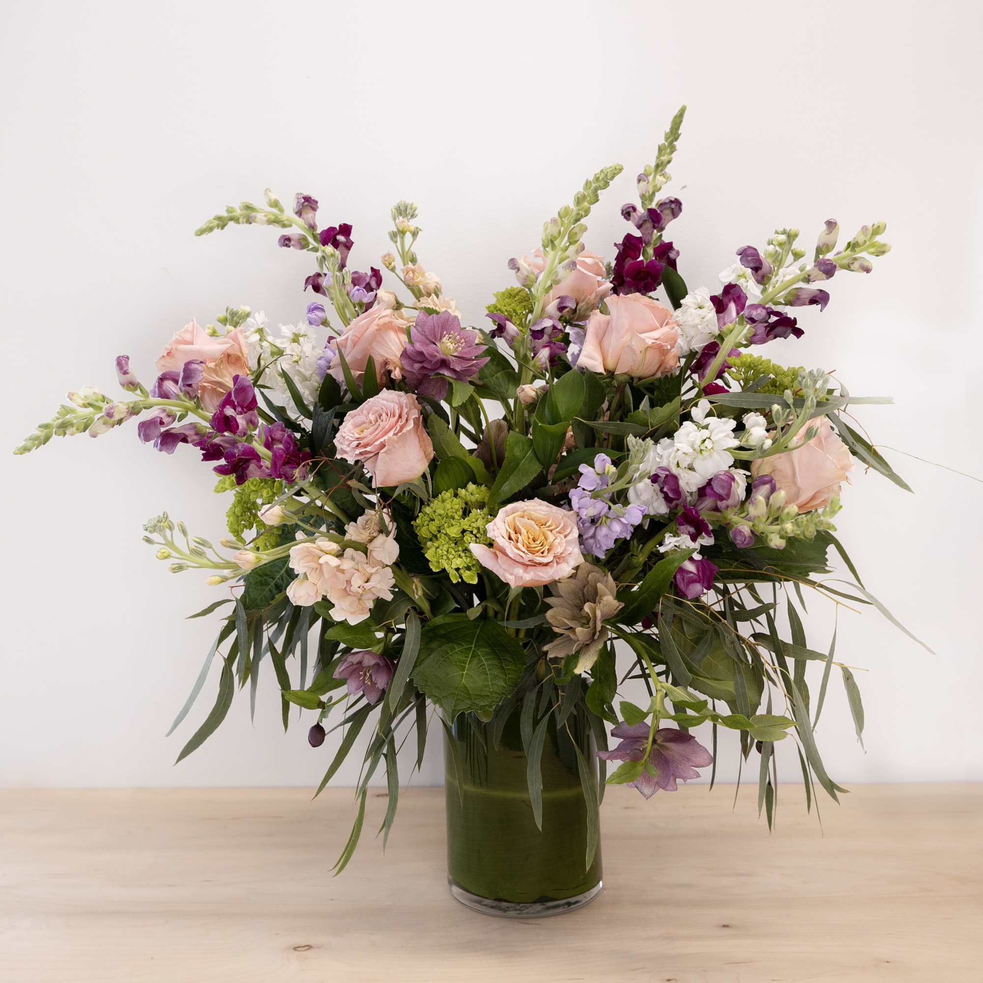 Mixed pink and purple flowers arranged in a glass vase