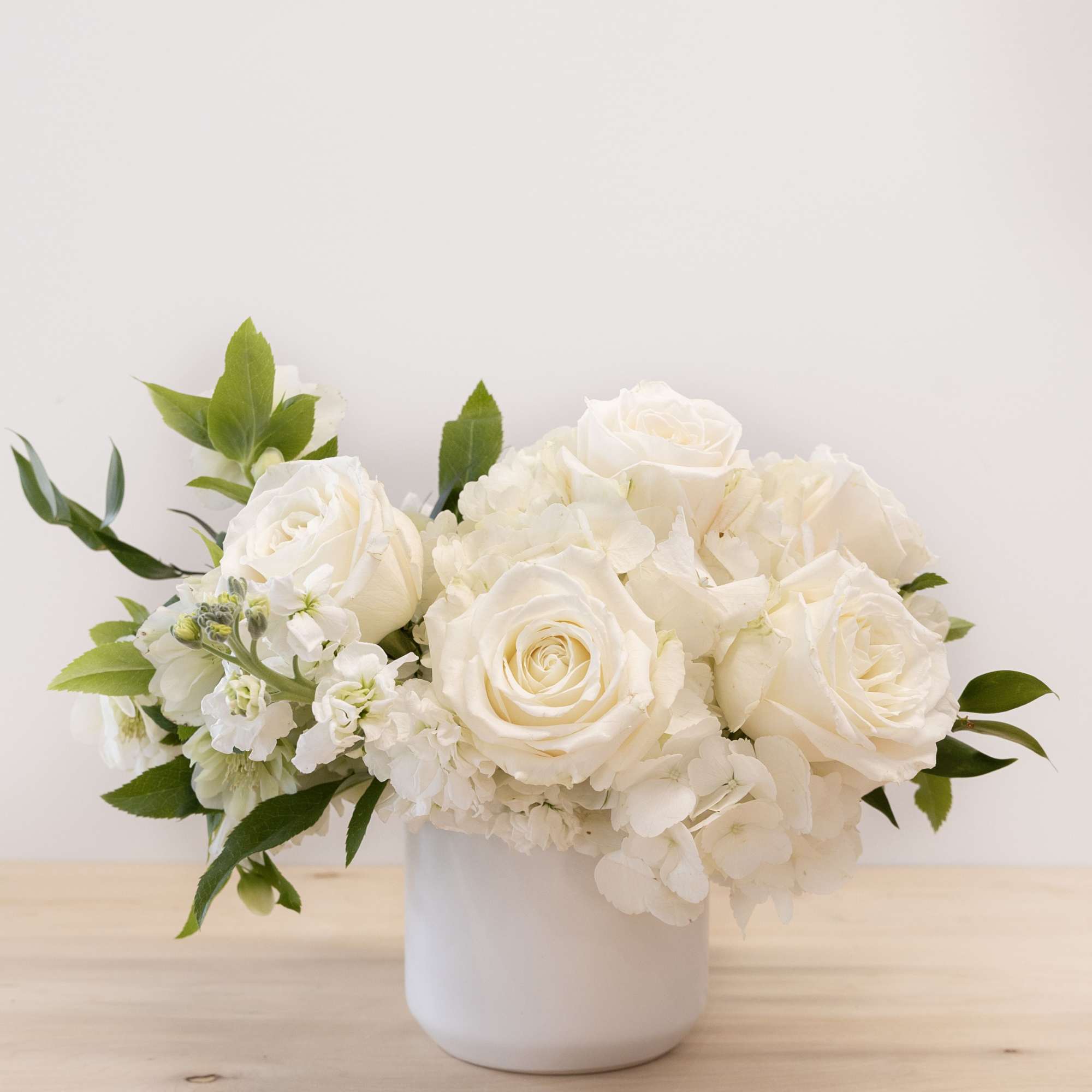 White roses and hydrangeas arranged in a white vase