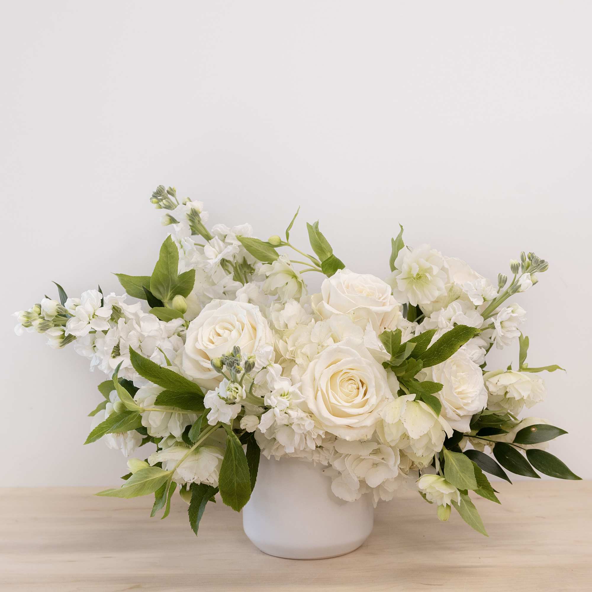 White rose and hydrangea arrangement in a white vase