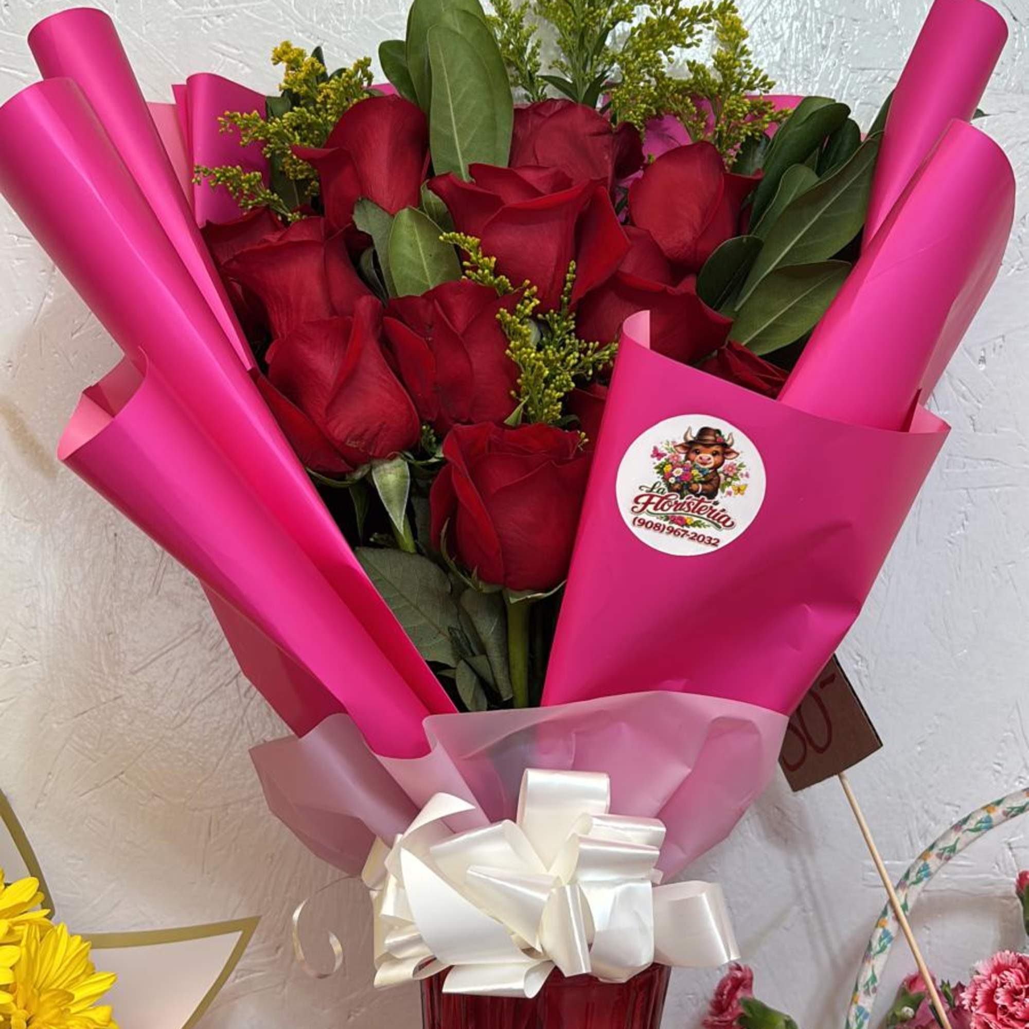 Bouquet of red roses wrapped in bright pink paper with a white bow