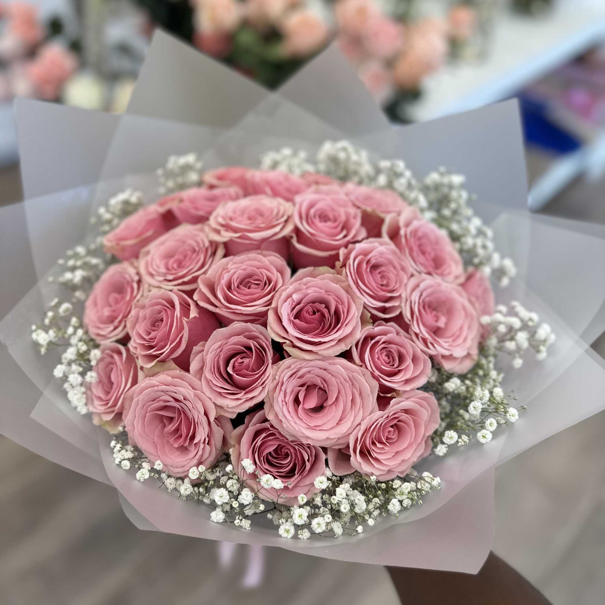 Bouquet of pink roses with white baby's breath in translucent wrap