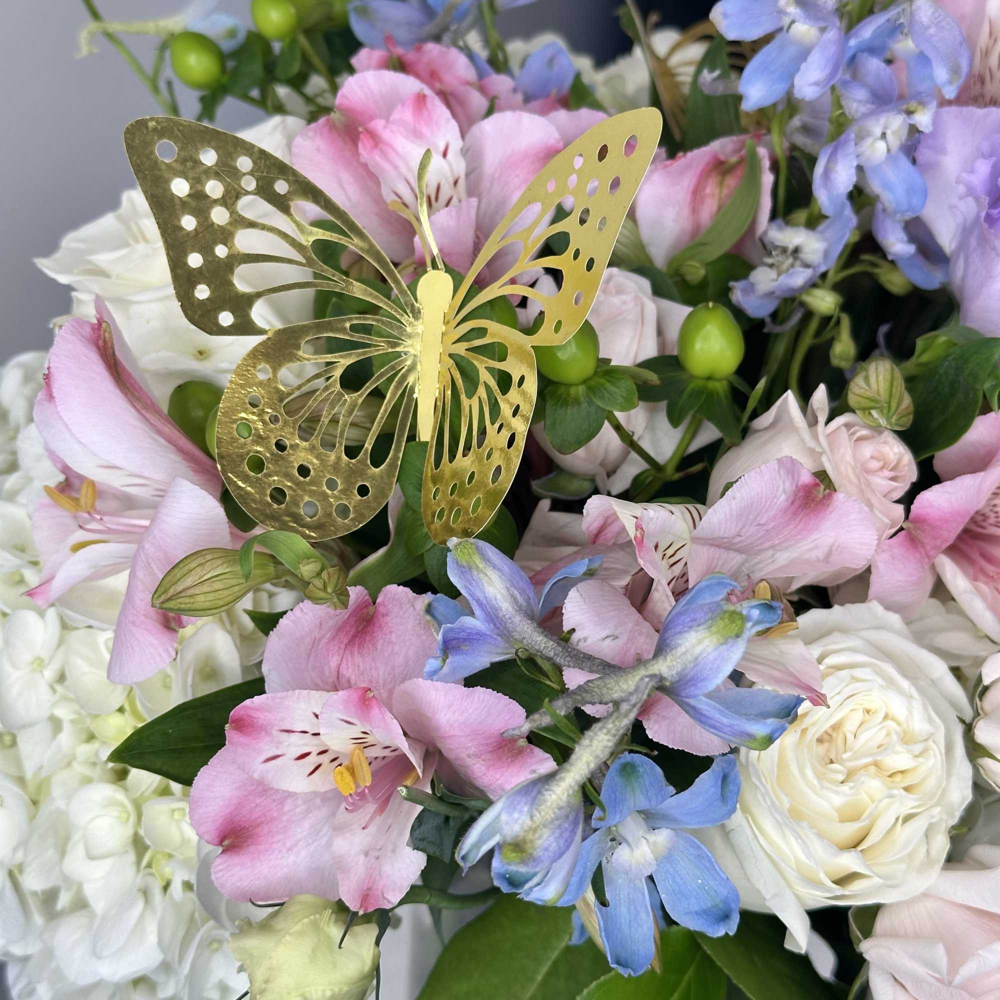 Pink and blue floral bouquet with a gold butterfly pick