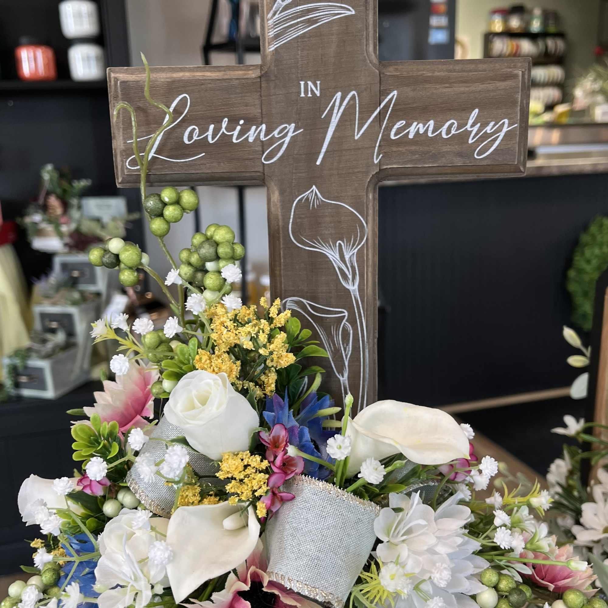 Wooden memorial cross with a mixed white floral arrangement