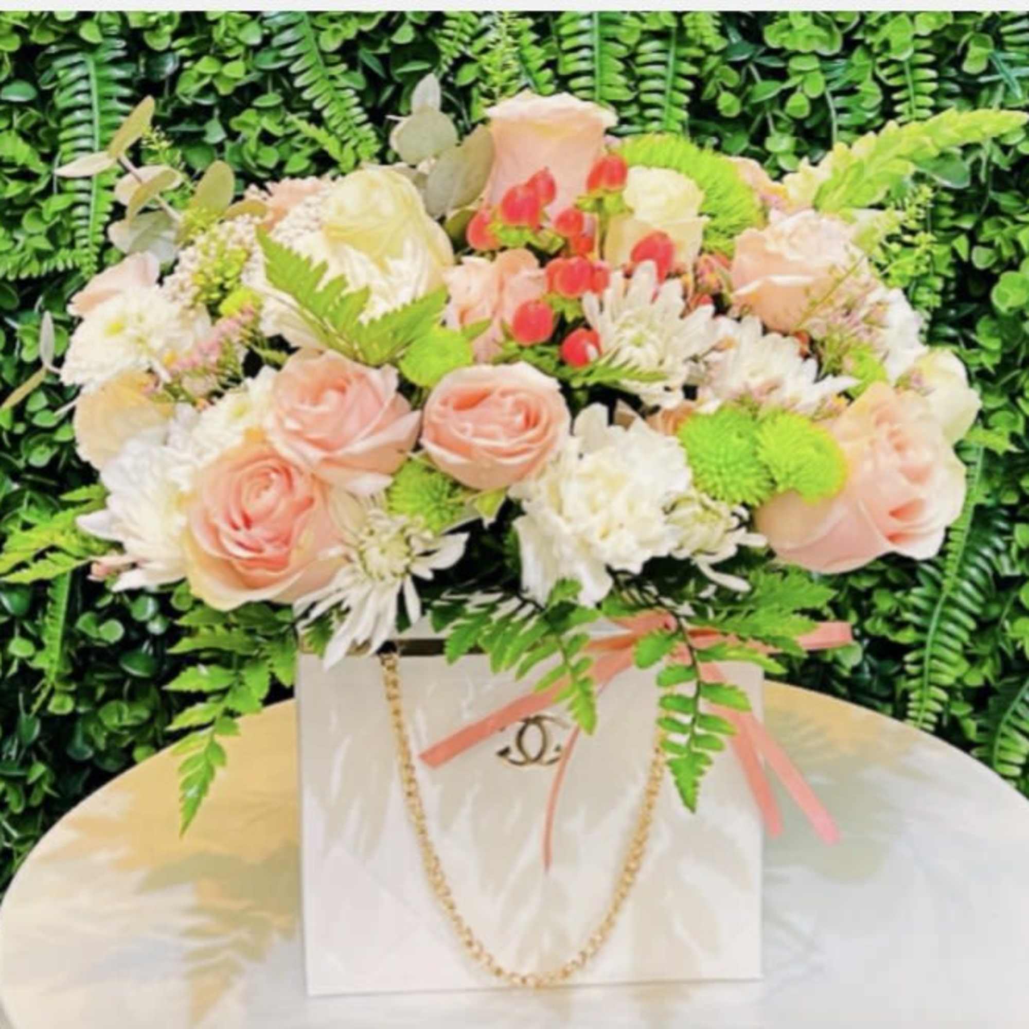 Pink and white rose arrangement in a white gift bag with ribbon