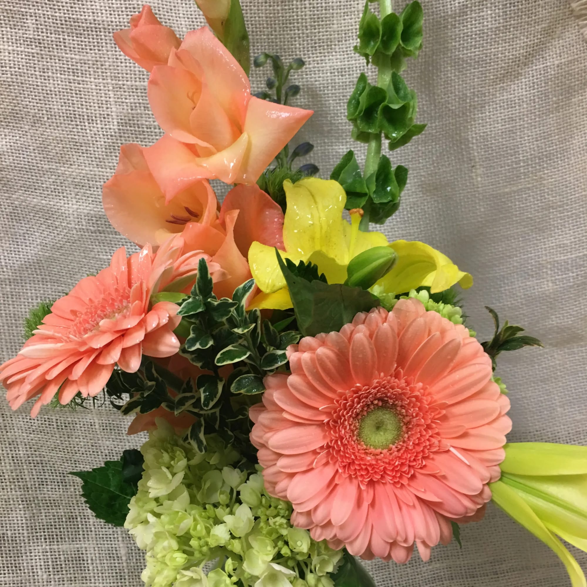 Bouquet of peach and yellow flowers in a green glass vase
