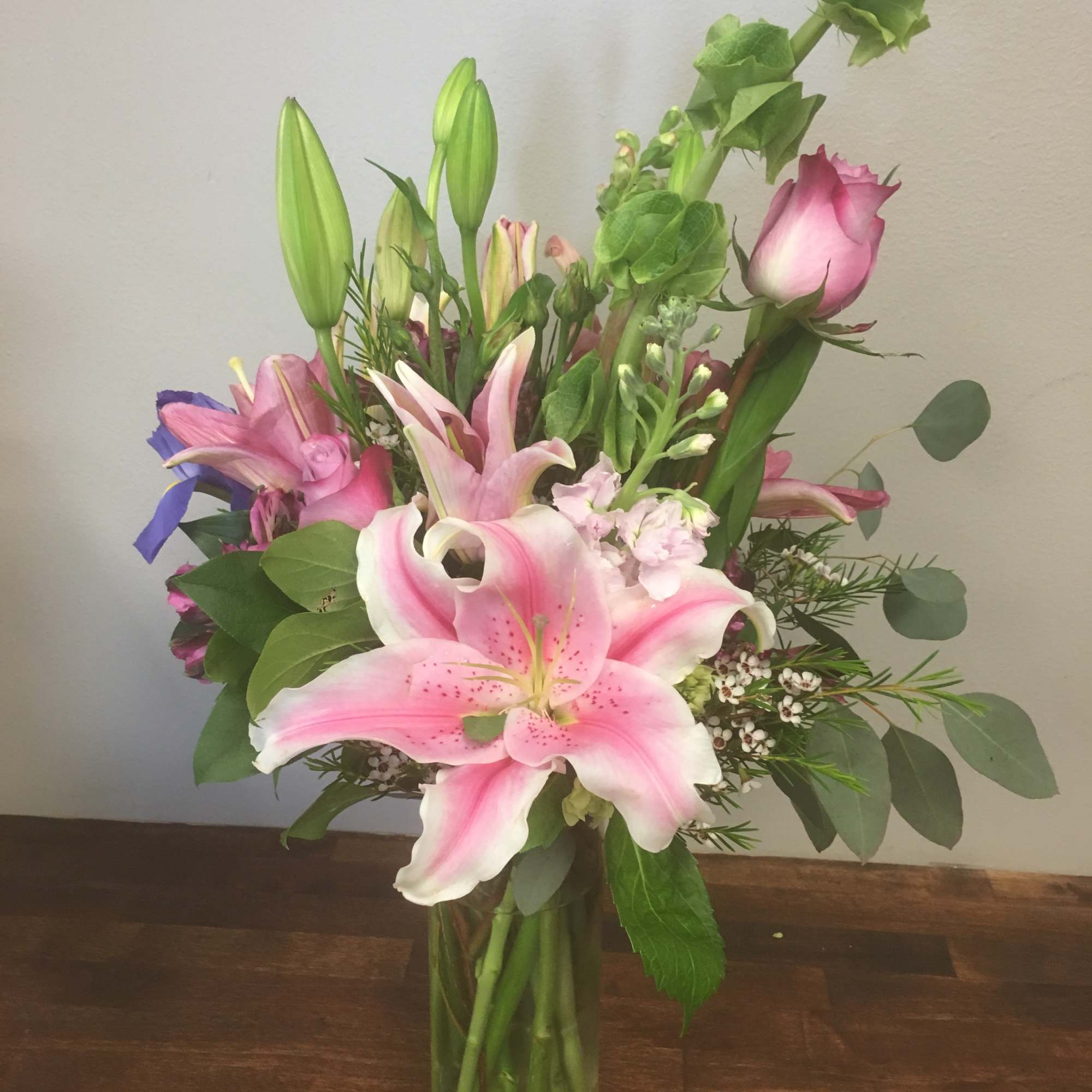 Pink lilies and roses arranged in a clear glass vase